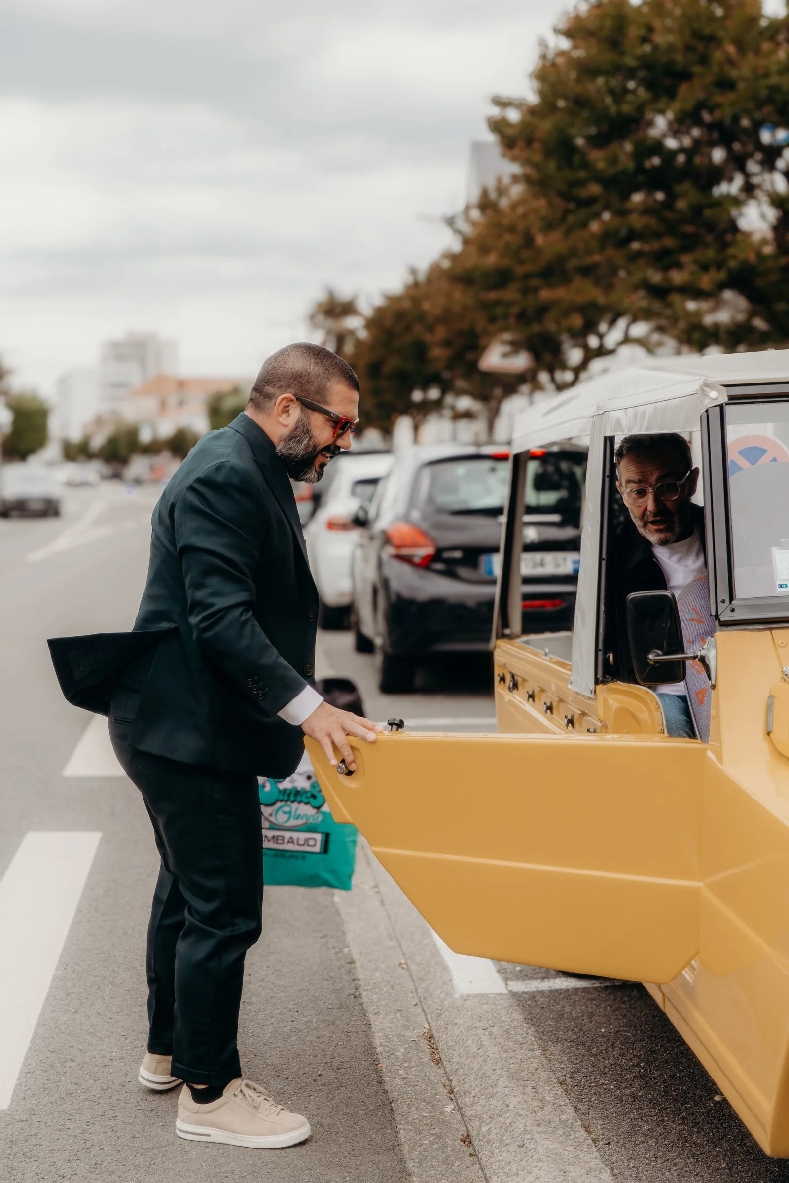 Le marié ouvre la porte de la voiture jaune