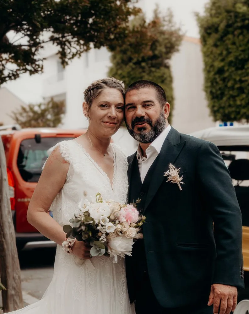Les mariés sourient, bouquet à la main