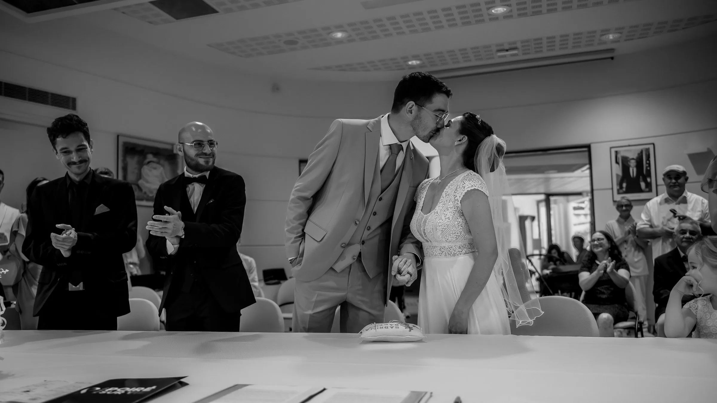 Baiser des mariés sous les applaudissements, en noir et blanc