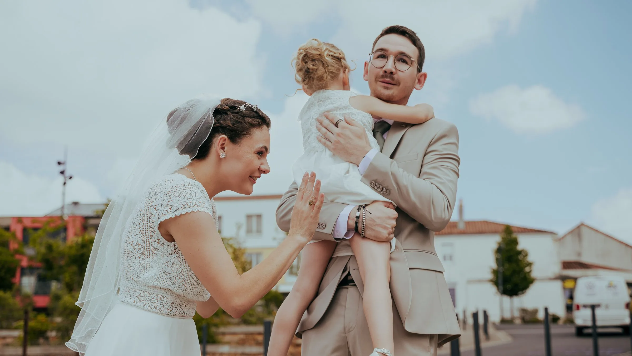 La mariée sourit à l’enfant que le marié porte dans ses bras