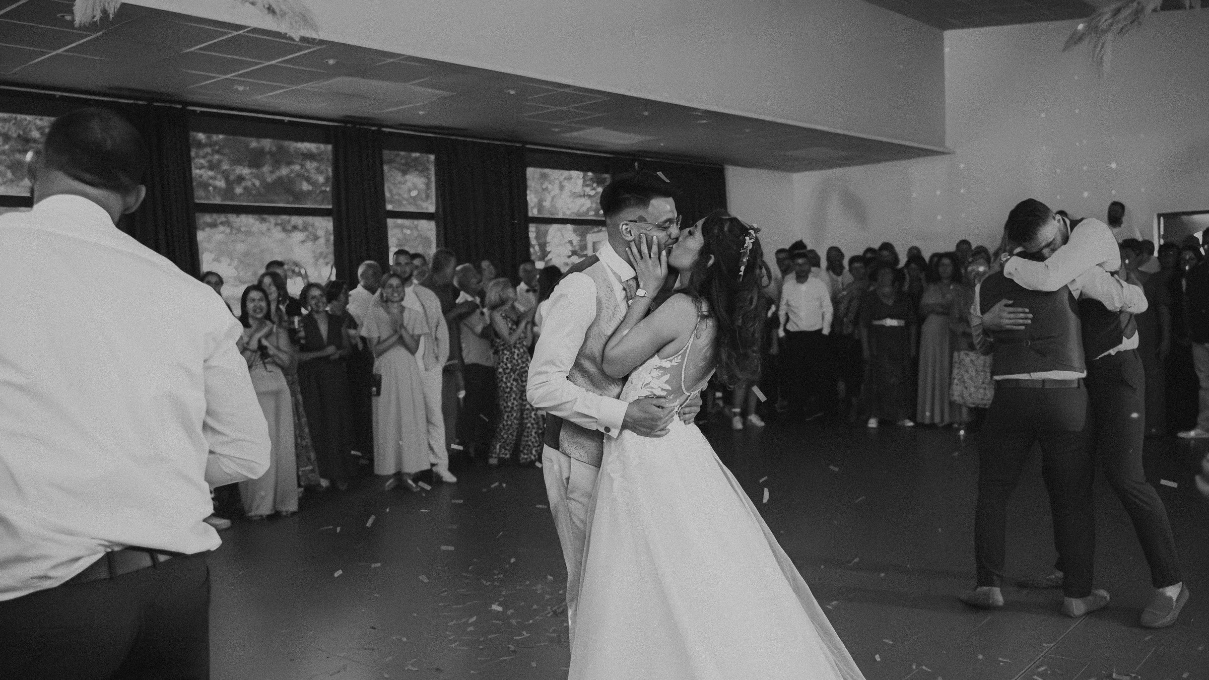 Baiser des mariés sur la piste de danse, en noir et blanc