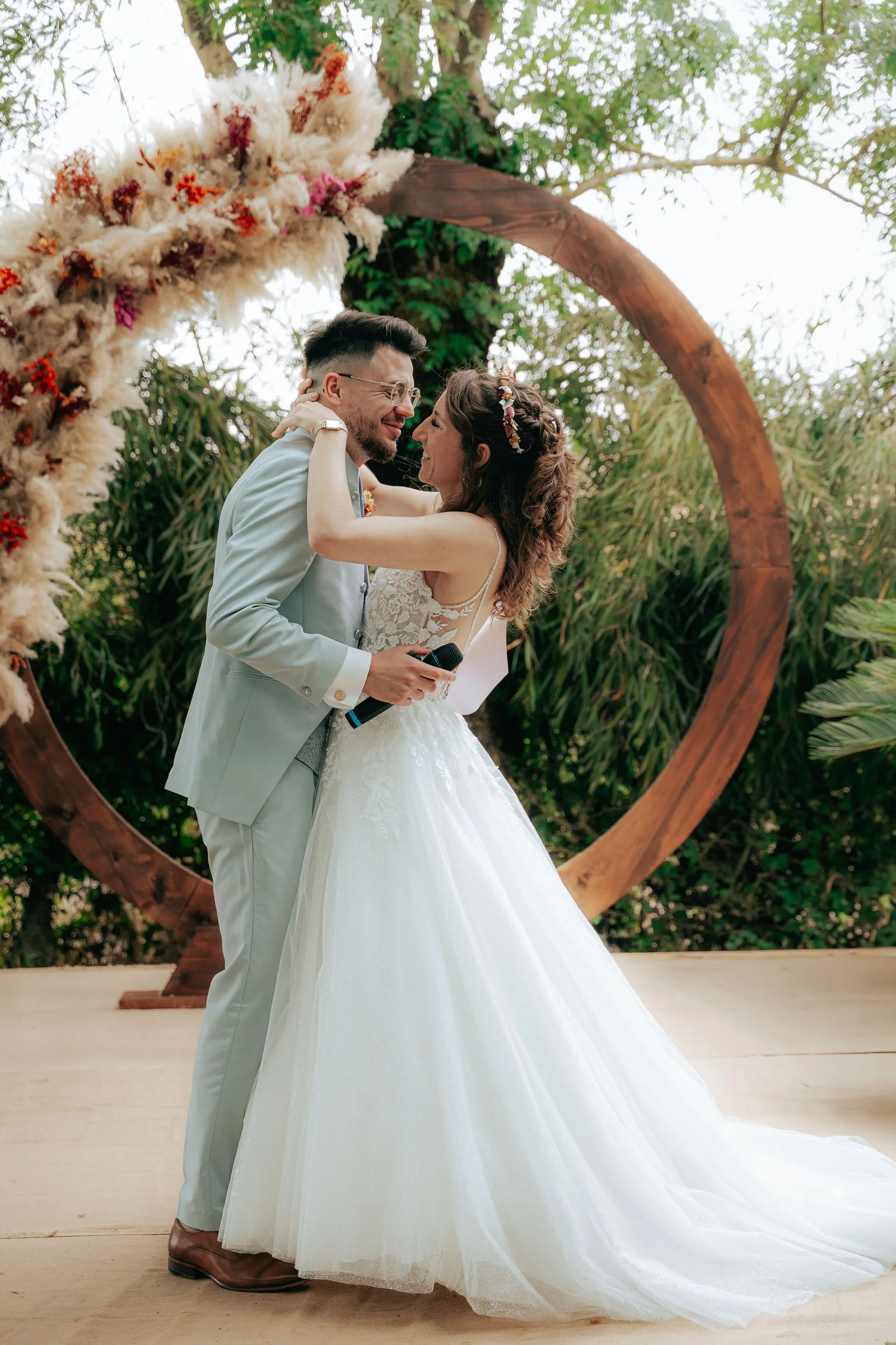 Le marié enlace la mariée sous l'arche en bois