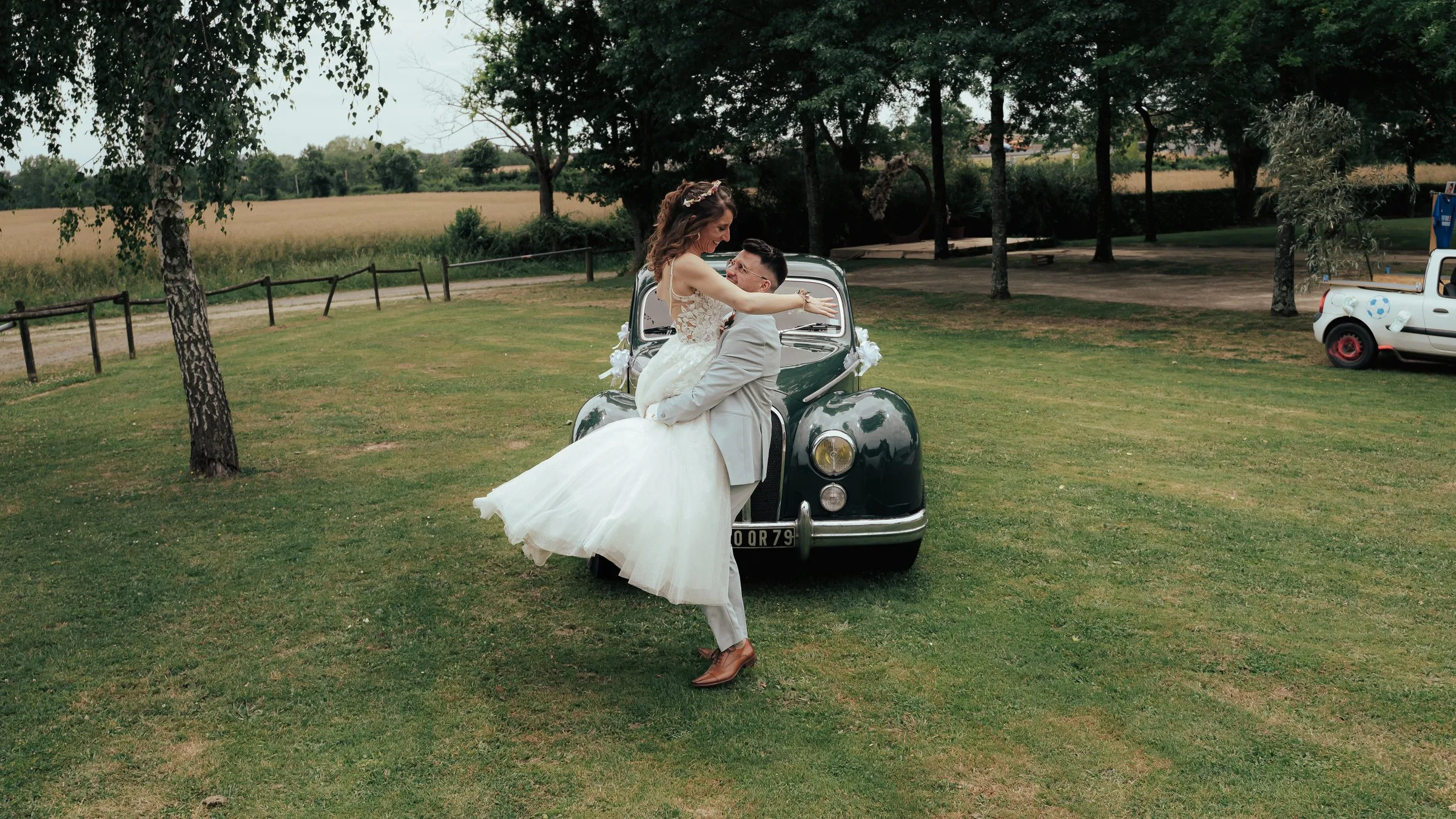 La mariée danse devant la voiture ancienne dans le parc