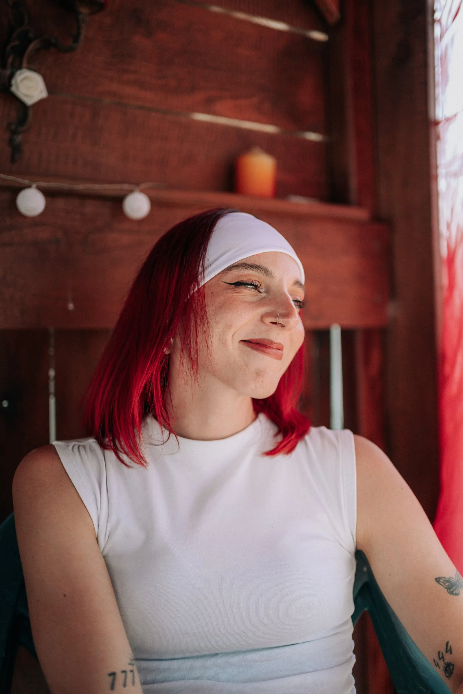 Une invitée aux cheveux rouges sourit sous la pergola en bois