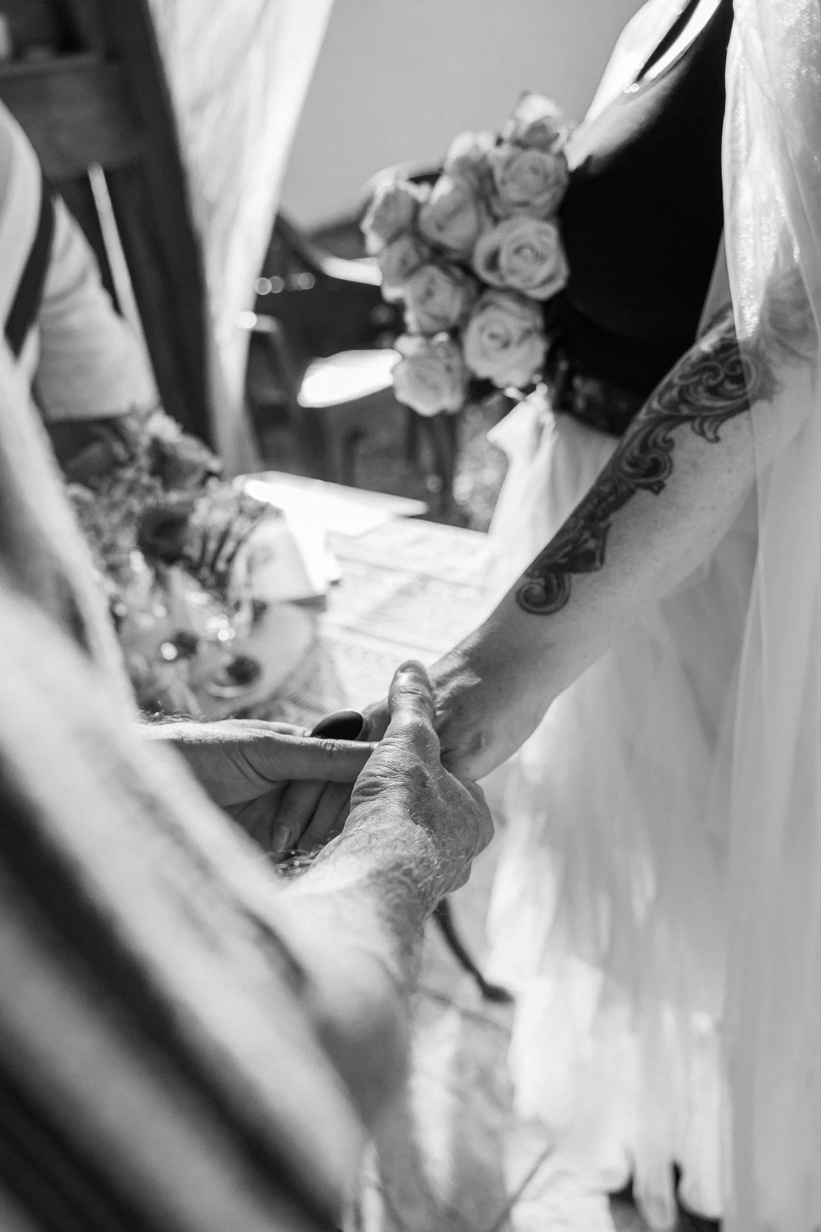 Les mains des mariés et le bouquet de roses, en noir et blanc
