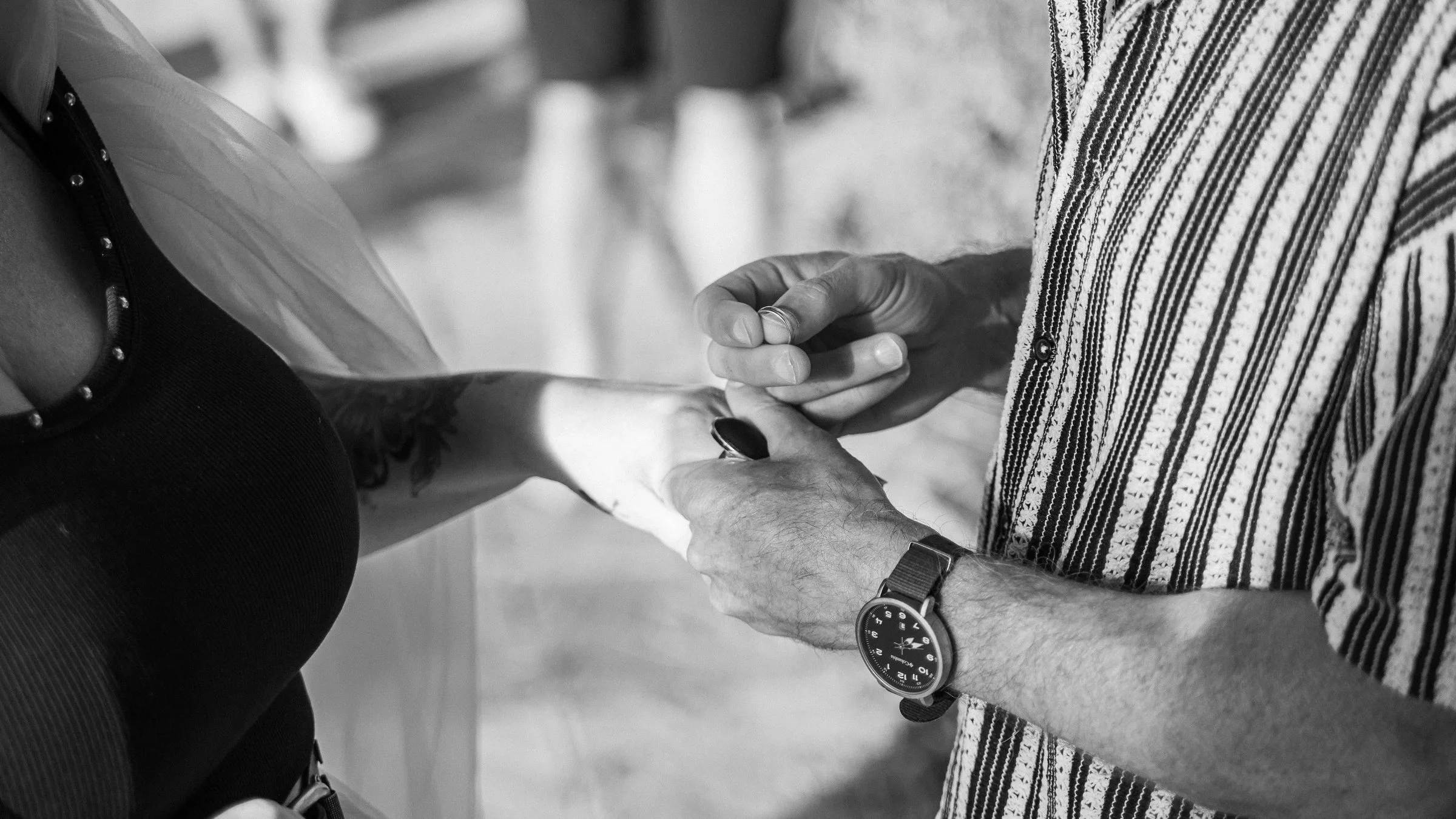 Le marié glisse l’alliance au doigt de la mariée, en noir et blanc