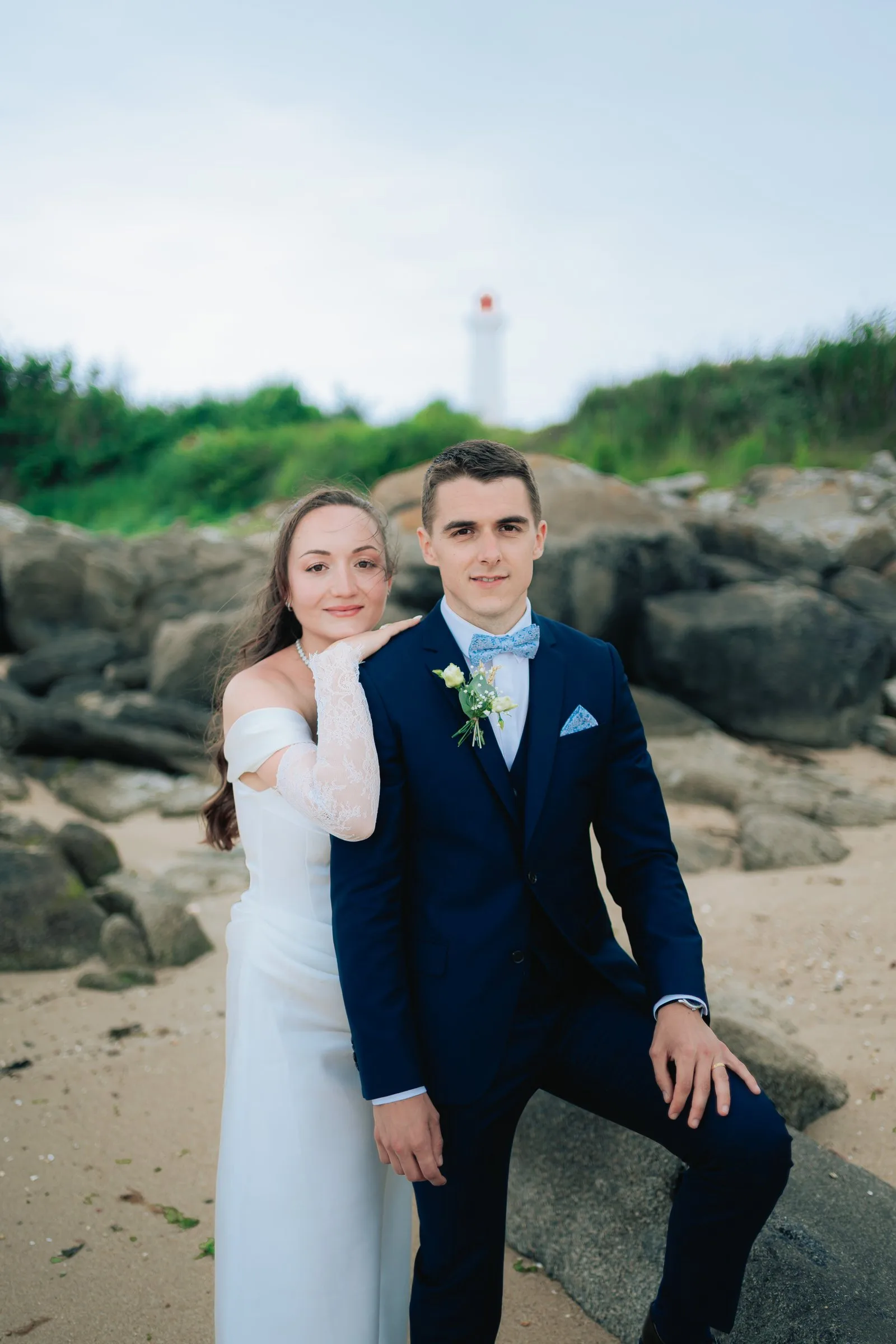 La mariée rit, appuyée contre le marié sur les rochers