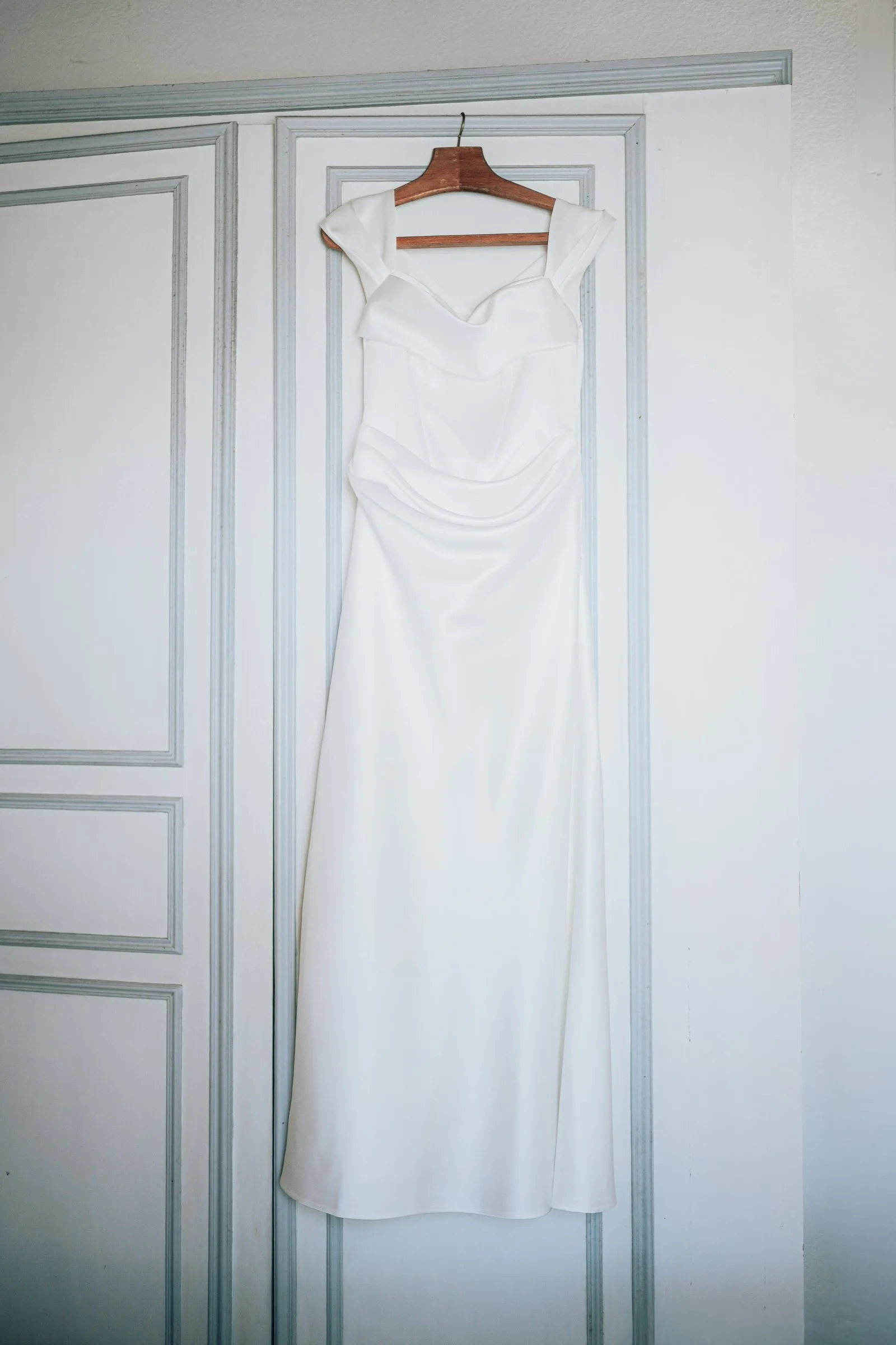 Robe de mariée suspendue à une porte blanche