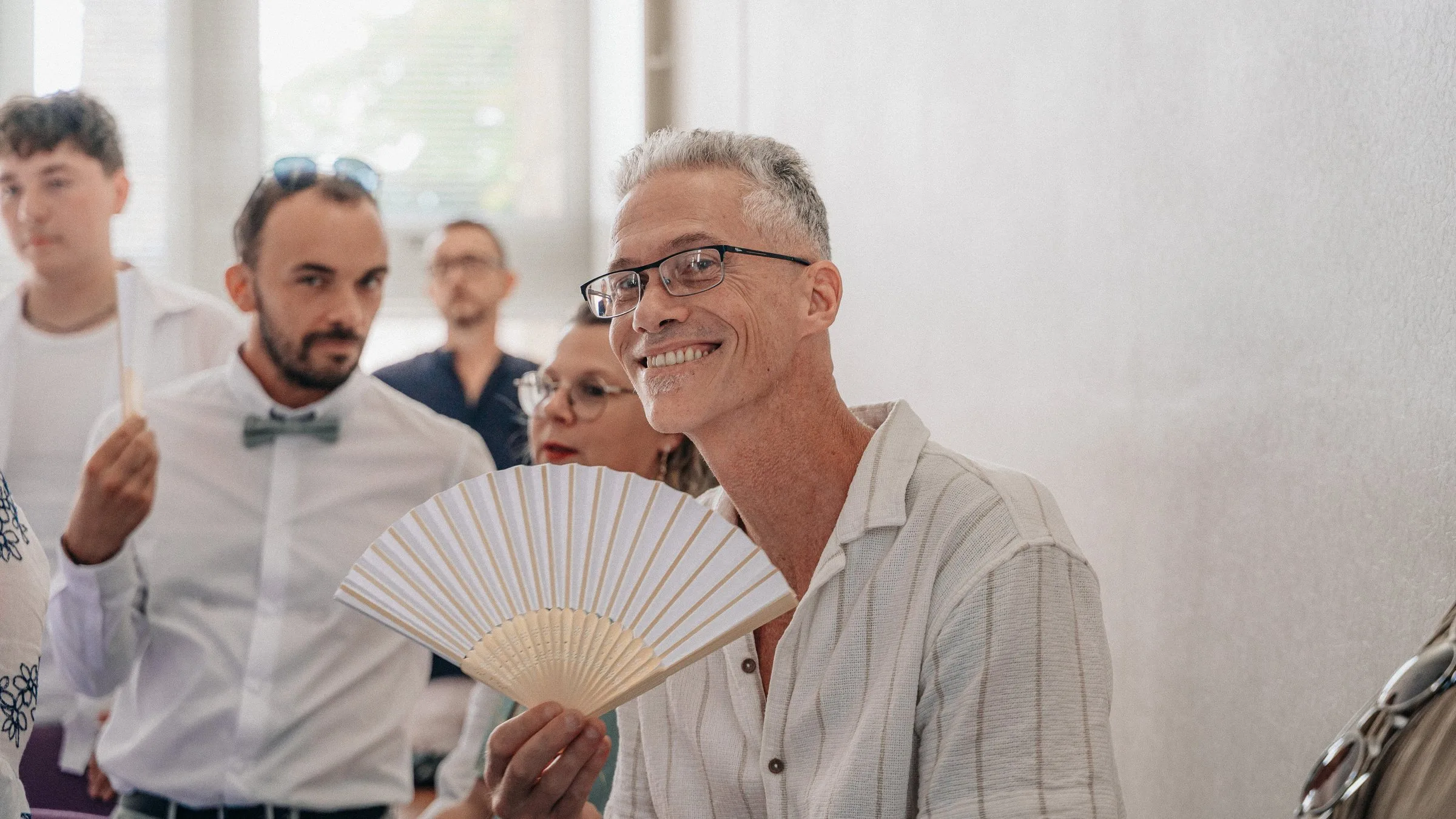 Des invités rient, éventail à la main