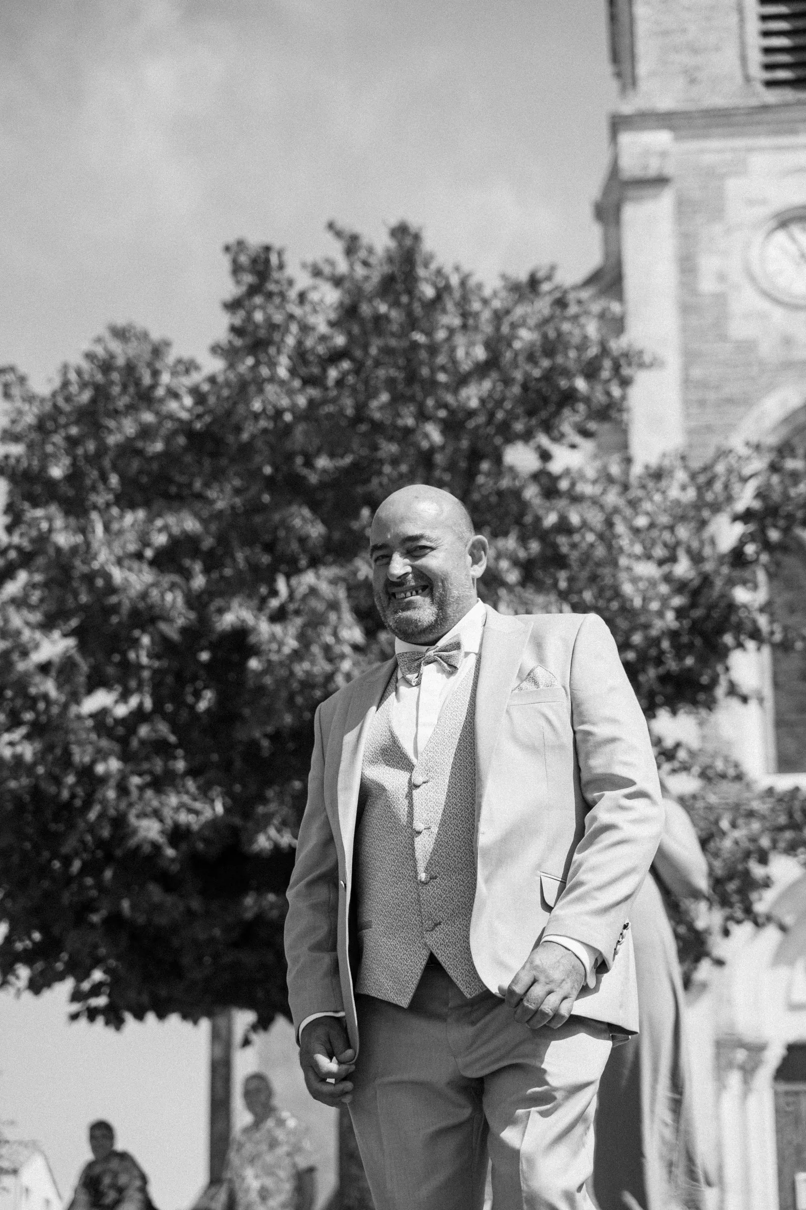 Le marié rit devant l’église, en noir et blanc