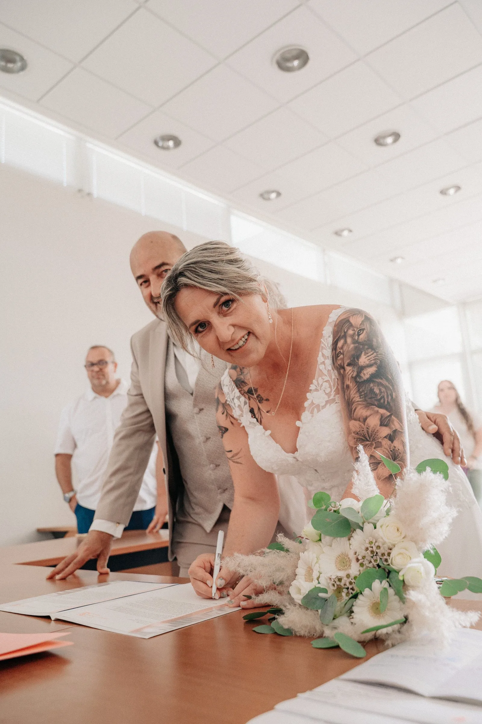 La mariée signe le registre en souriant