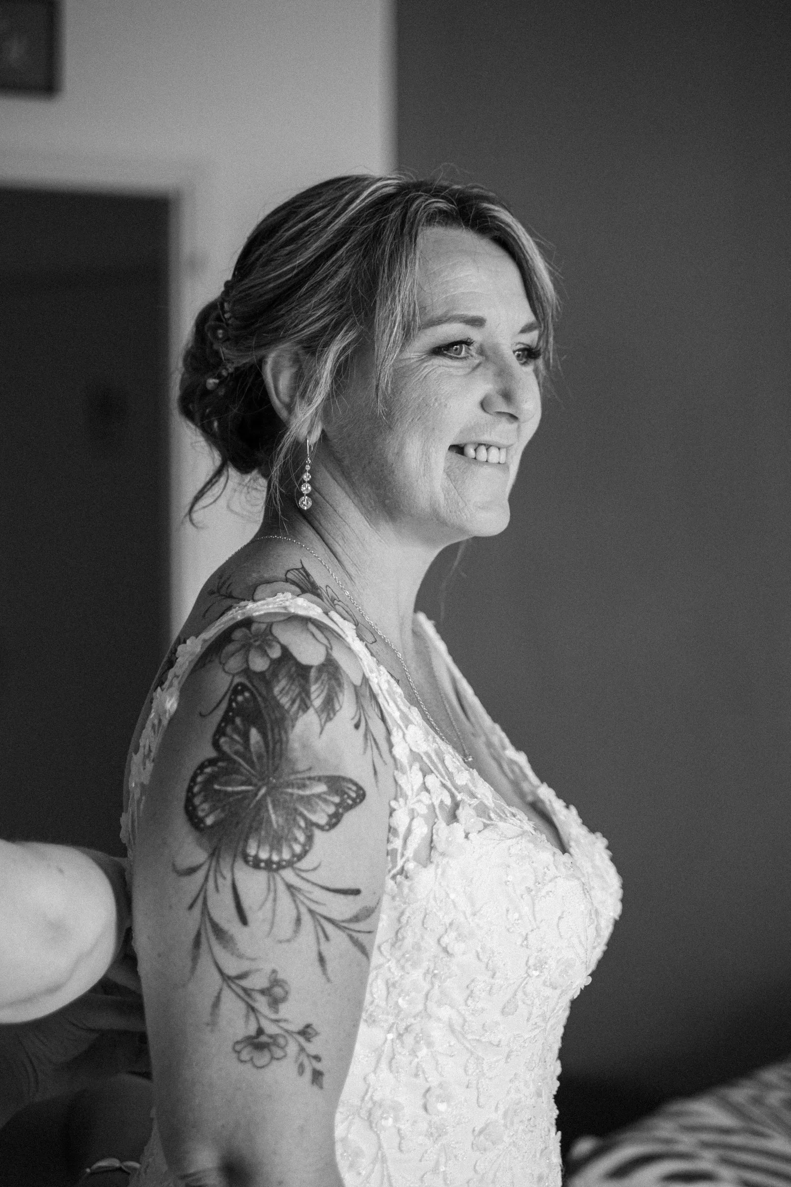 La mariée sourit pendant les préparatifs, en noir et blanc