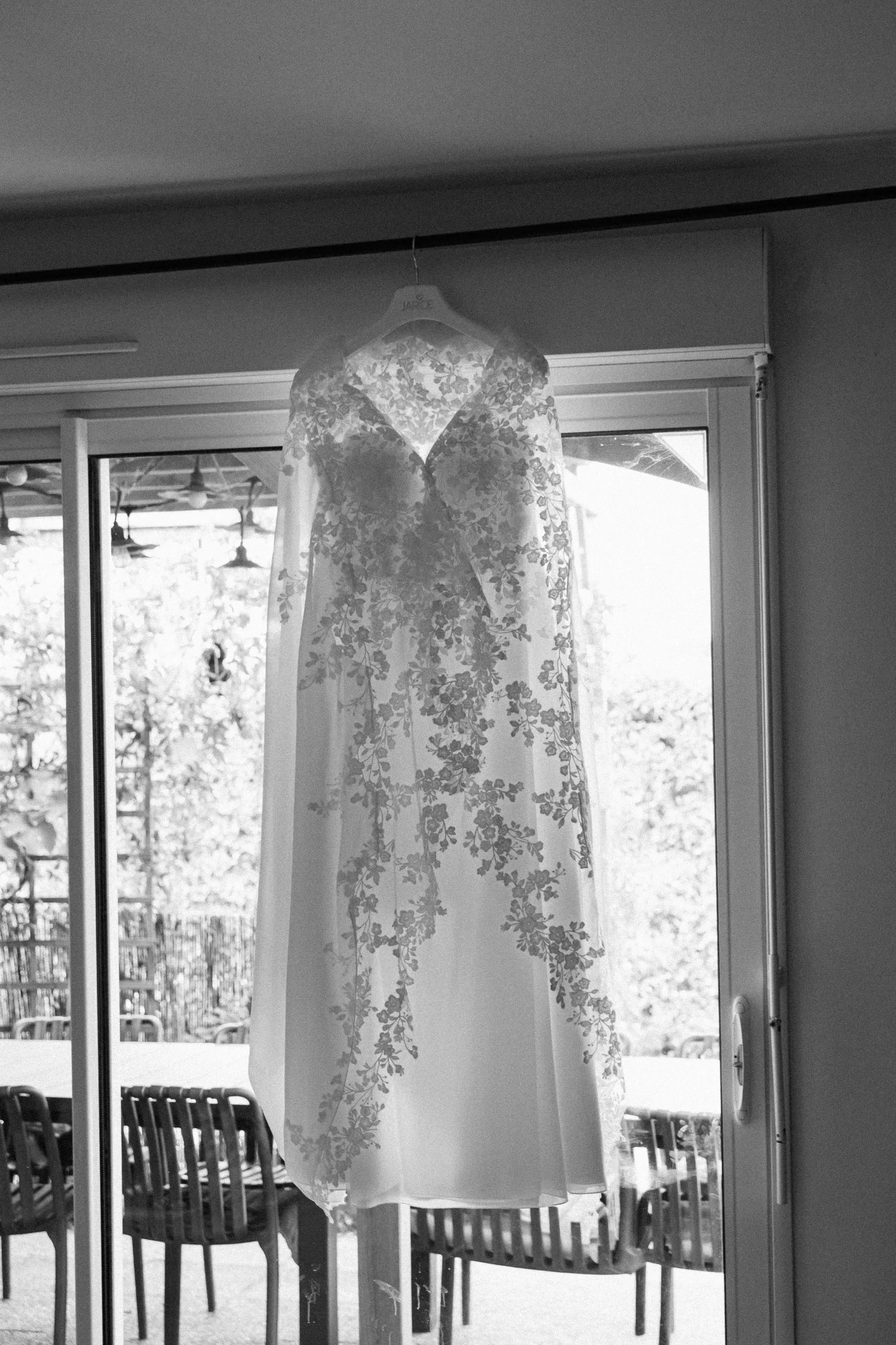 La robe de mariée suspendue devant la baie vitrée, en noir et blanc