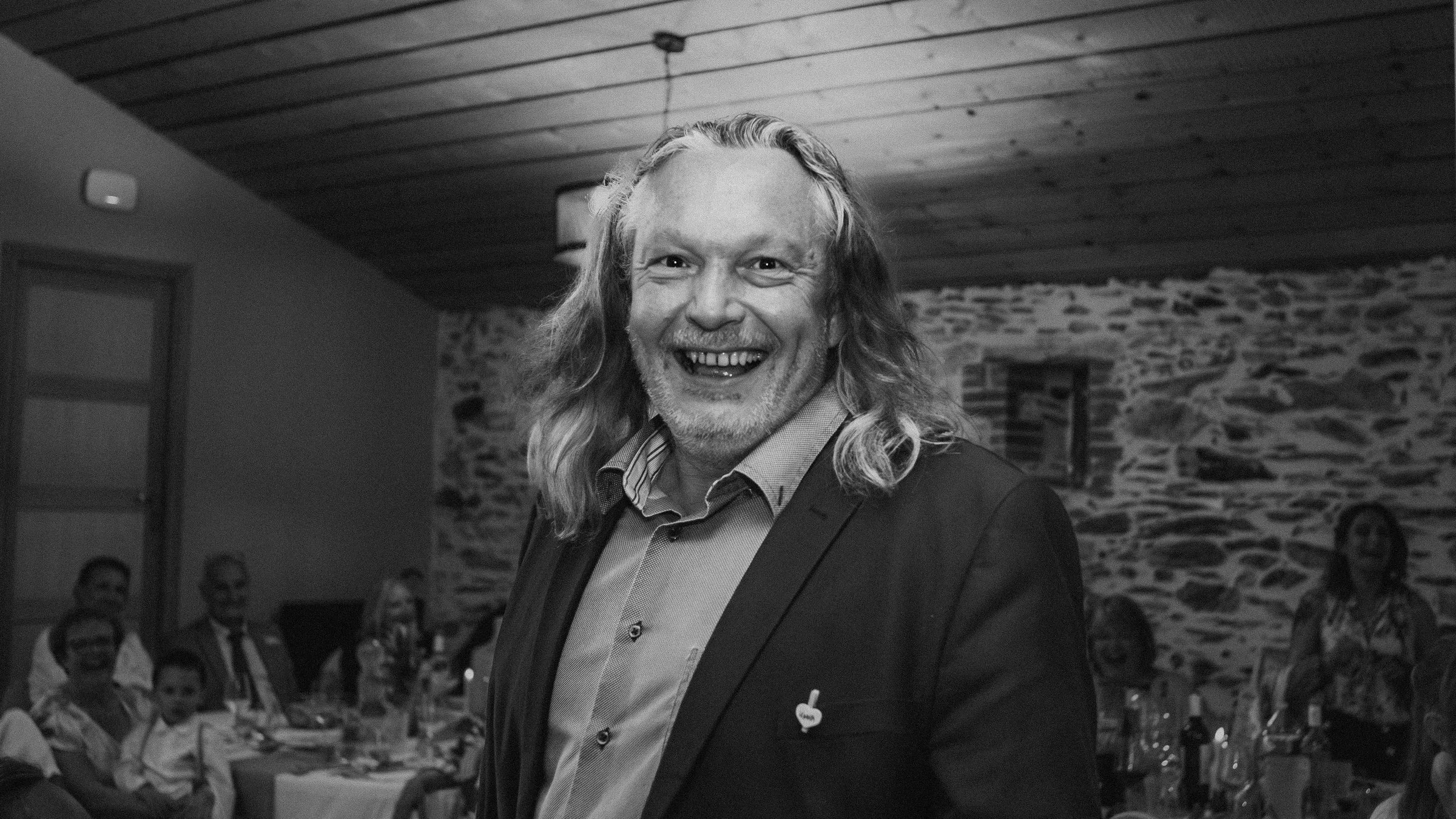 Un invité éclate de rire pendant la soirée, en noir et blanc
