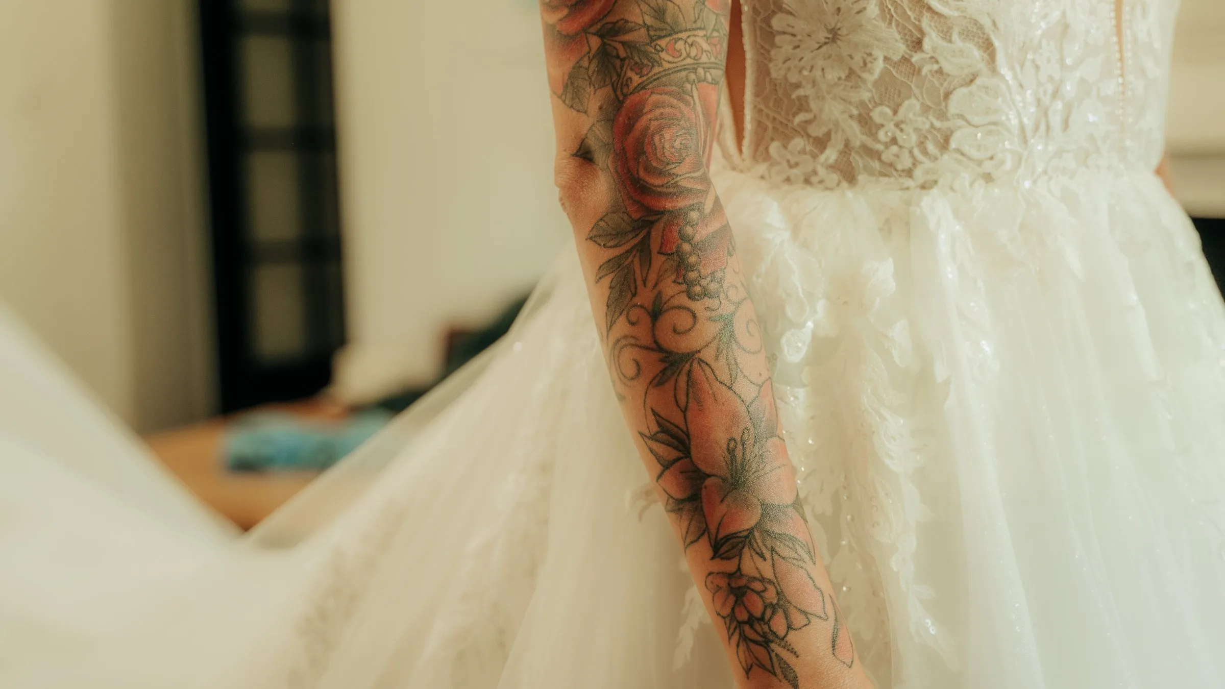 Le bras tatoué de la mariée sur la dentelle de sa robe