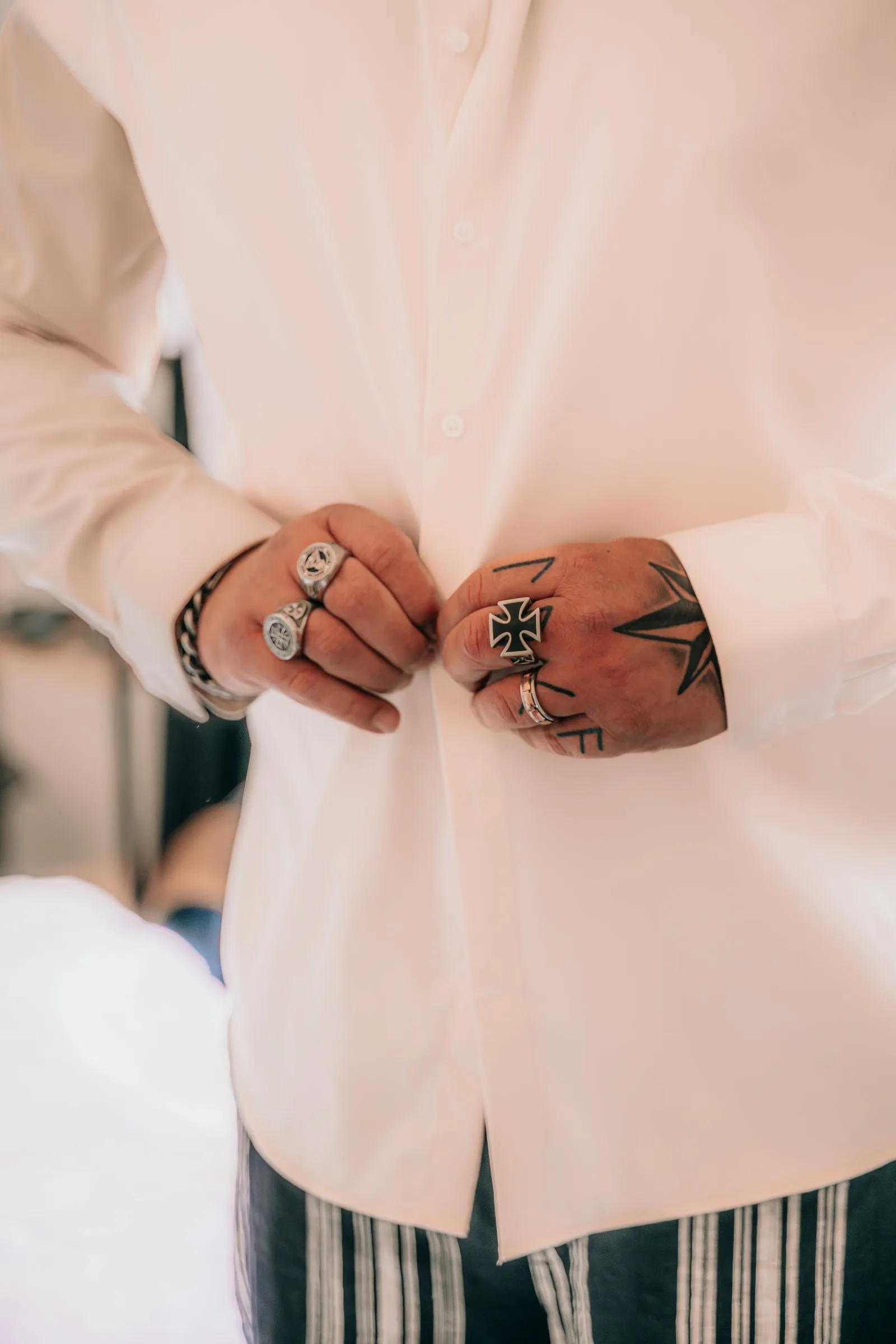 Les mains baguées du marié sur sa chemise