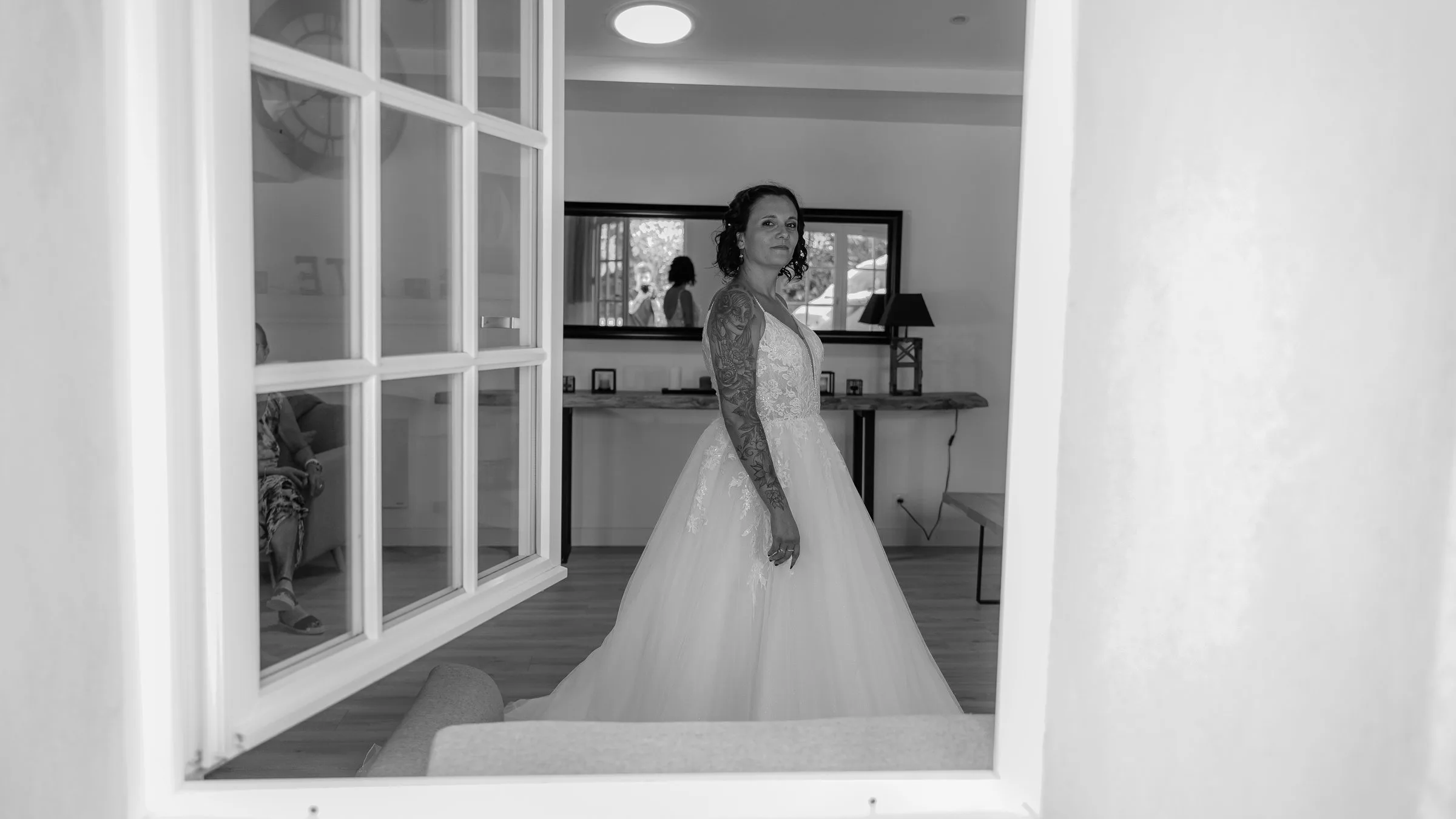 La mariée prête, vue à travers une porte vitrée, en noir et blanc
