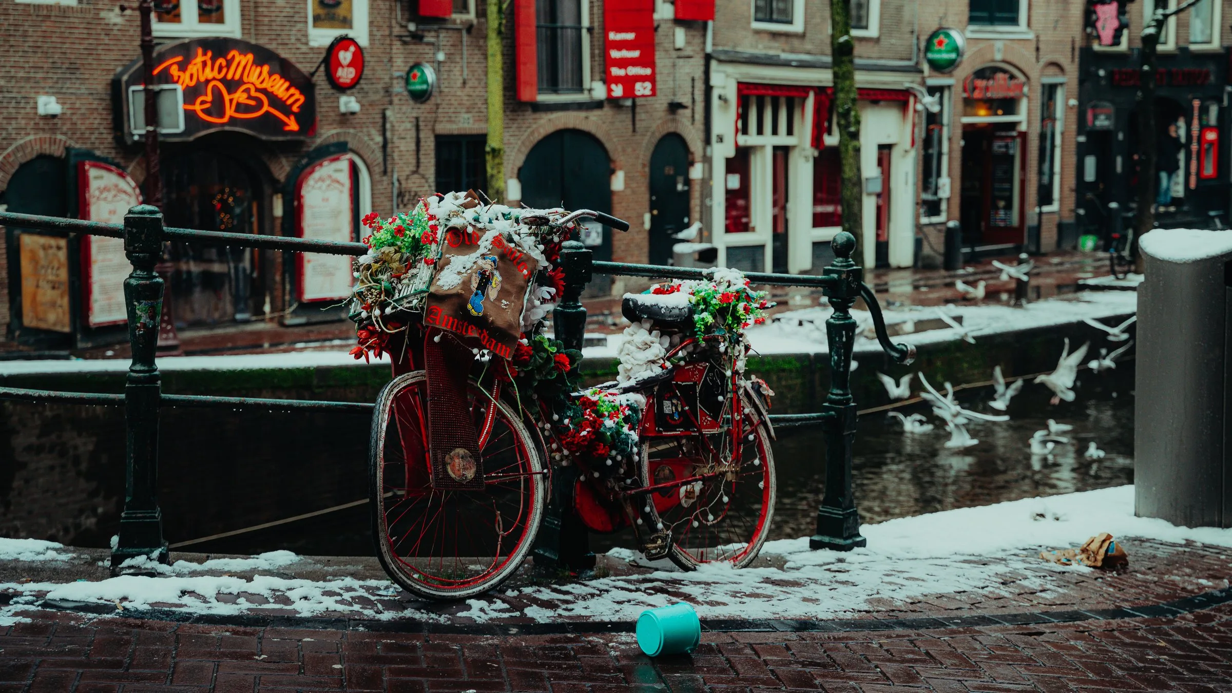 Un vélo fleuri et enneigé au bord d’un canal d’Amsterdam