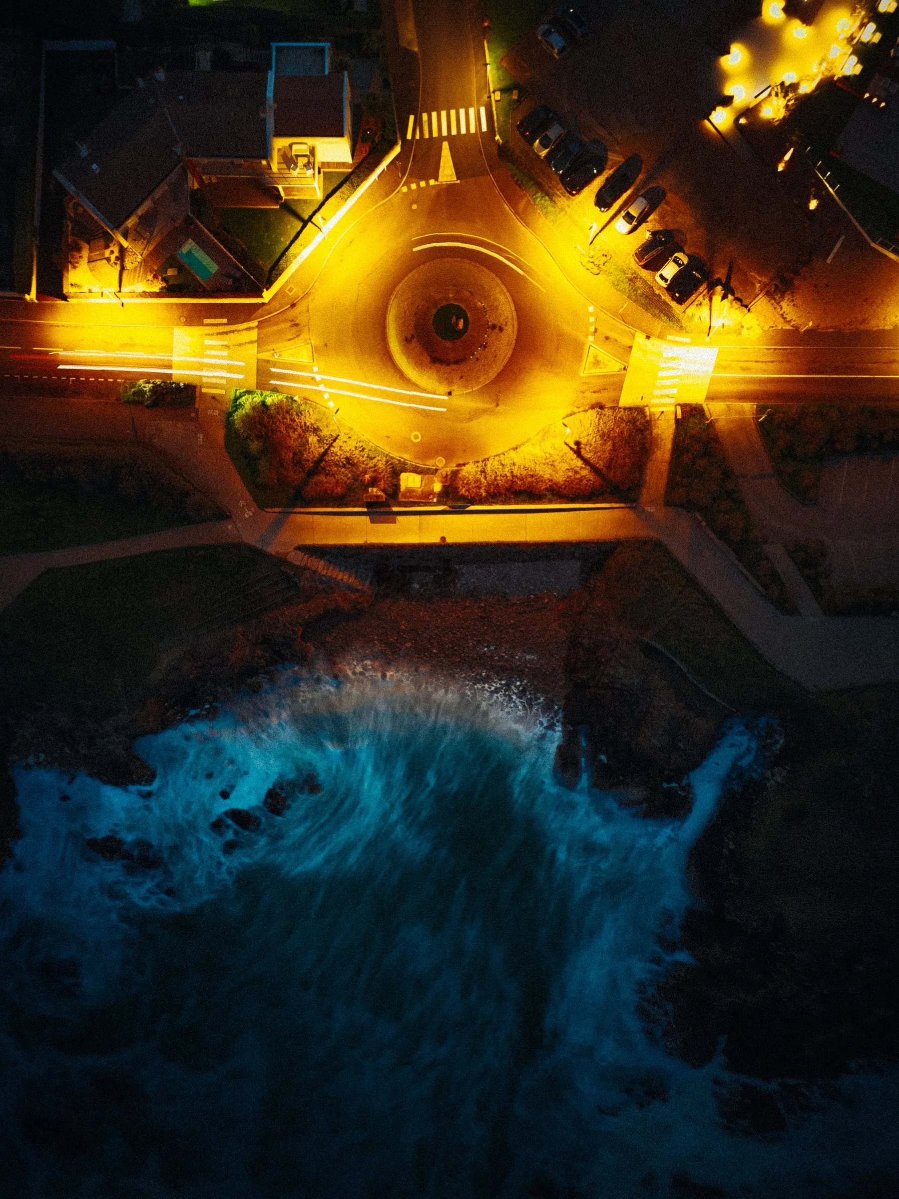 Vue aérienne d’un rond-point illuminé au bord de l’océan, la nuit