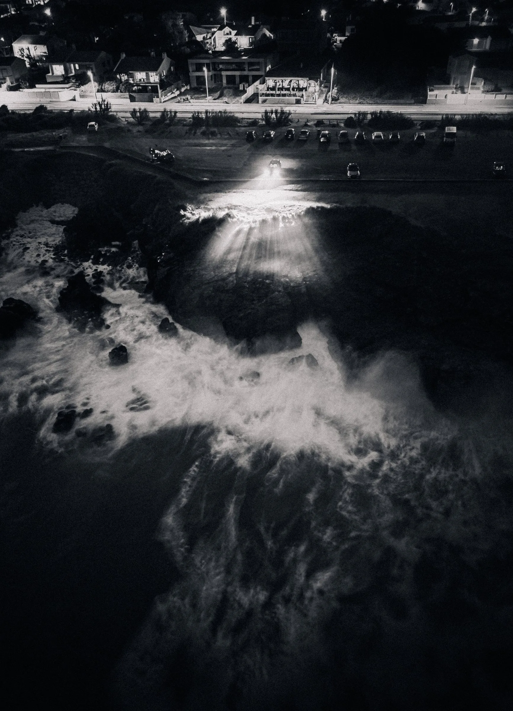 Vue aérienne des vagues sur les rochers la nuit, en noir et blanc