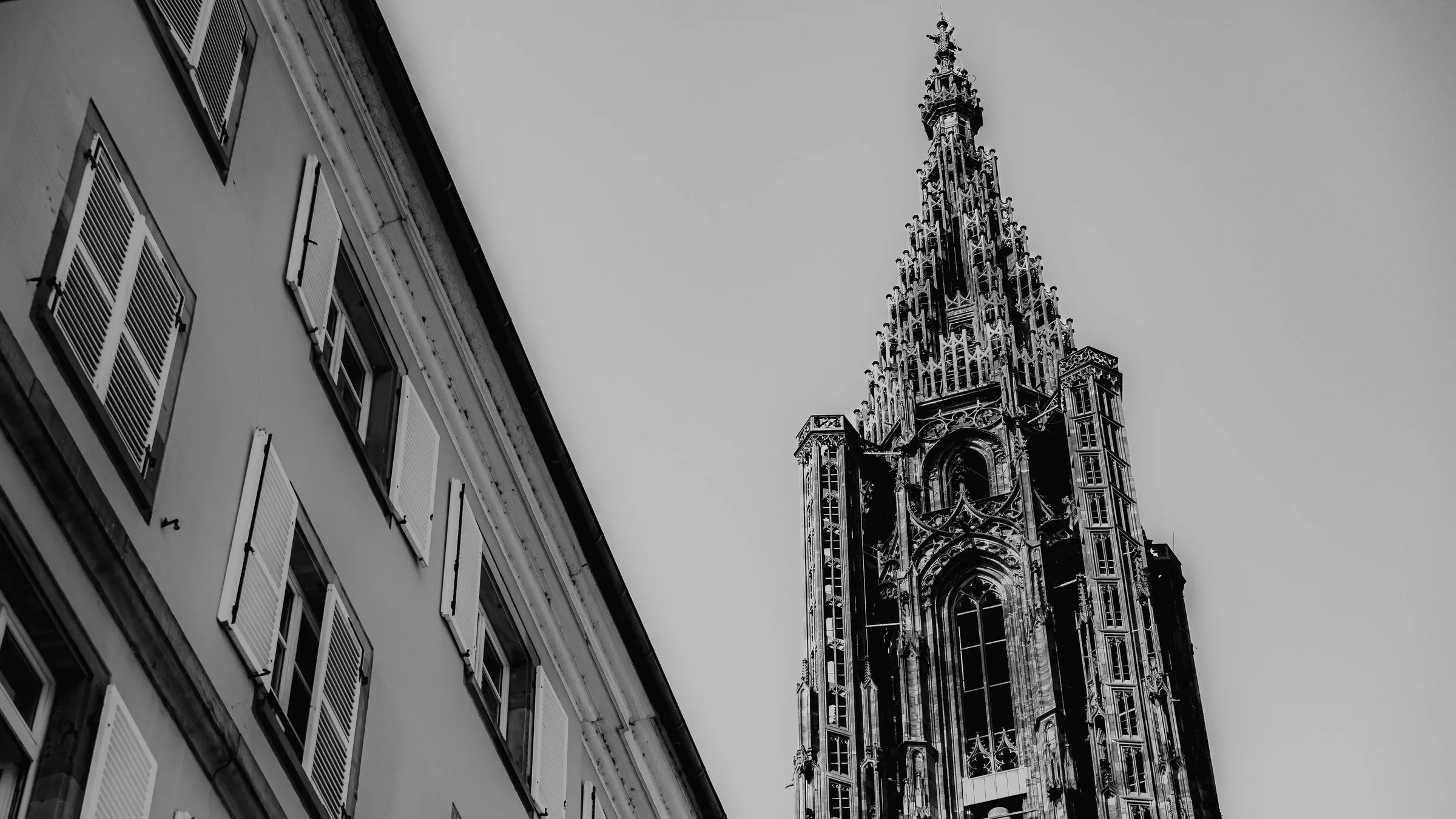 La flèche de la cathédrale de Strasbourg au bout d’une rue, en noir et blanc