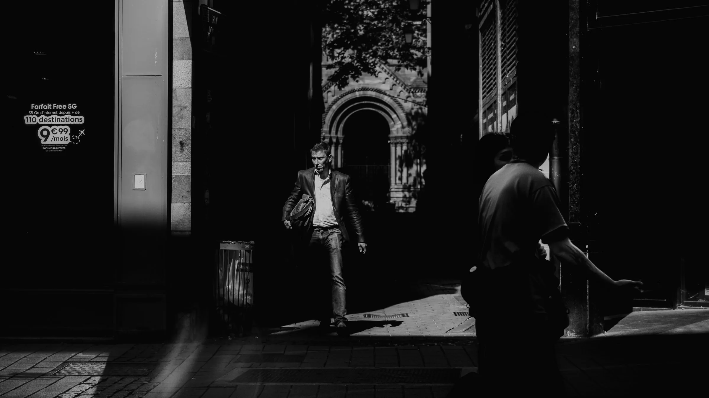 Des passants à contre-jour dans une ruelle sombre