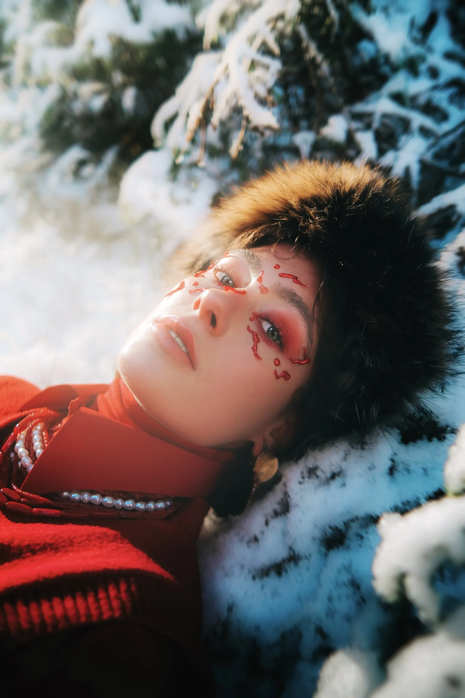 Femme au bonnet de fourrure allongée dans la neige