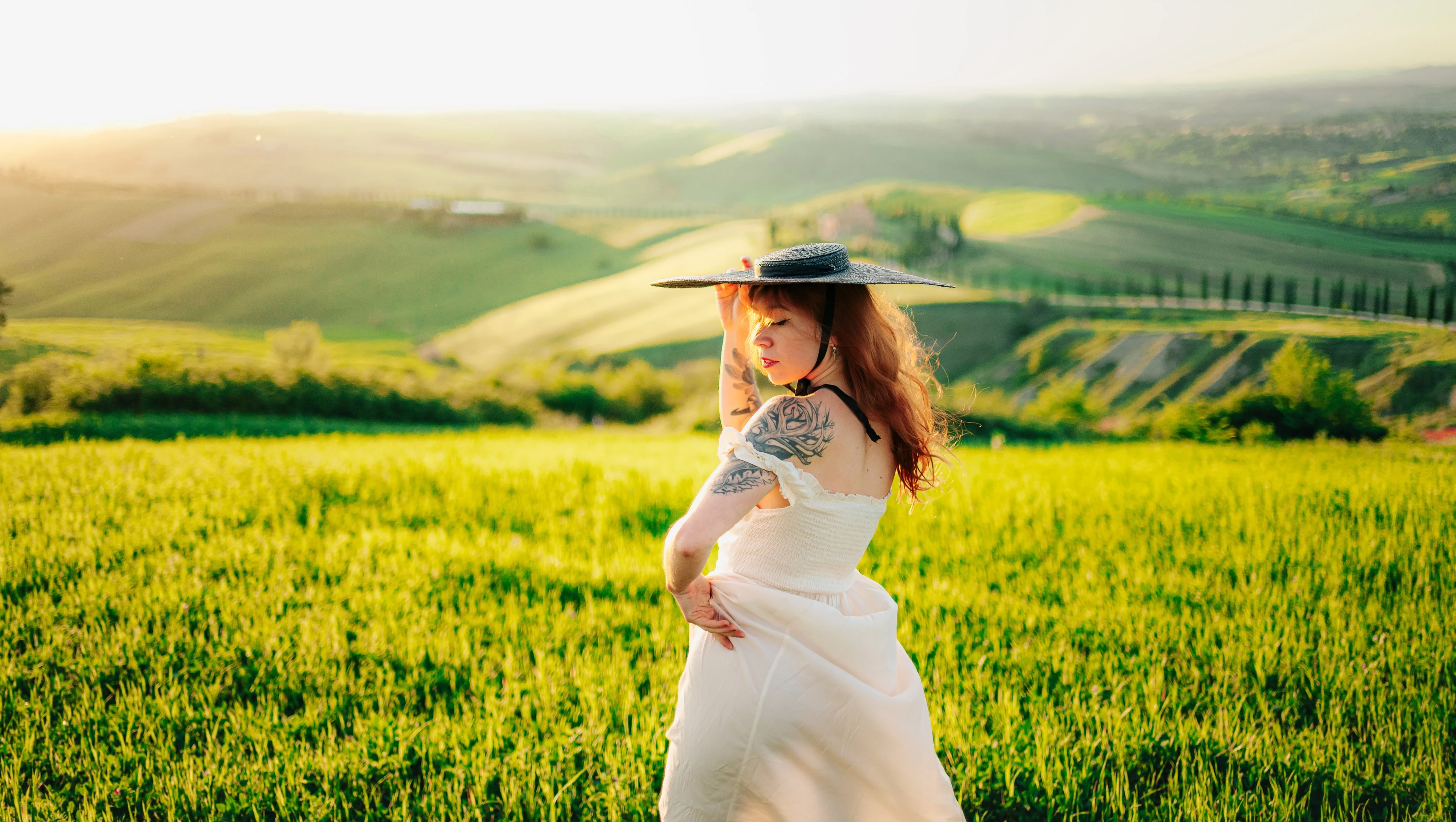 Femme au chapeau dans un champ au soleil, collines de Toscane