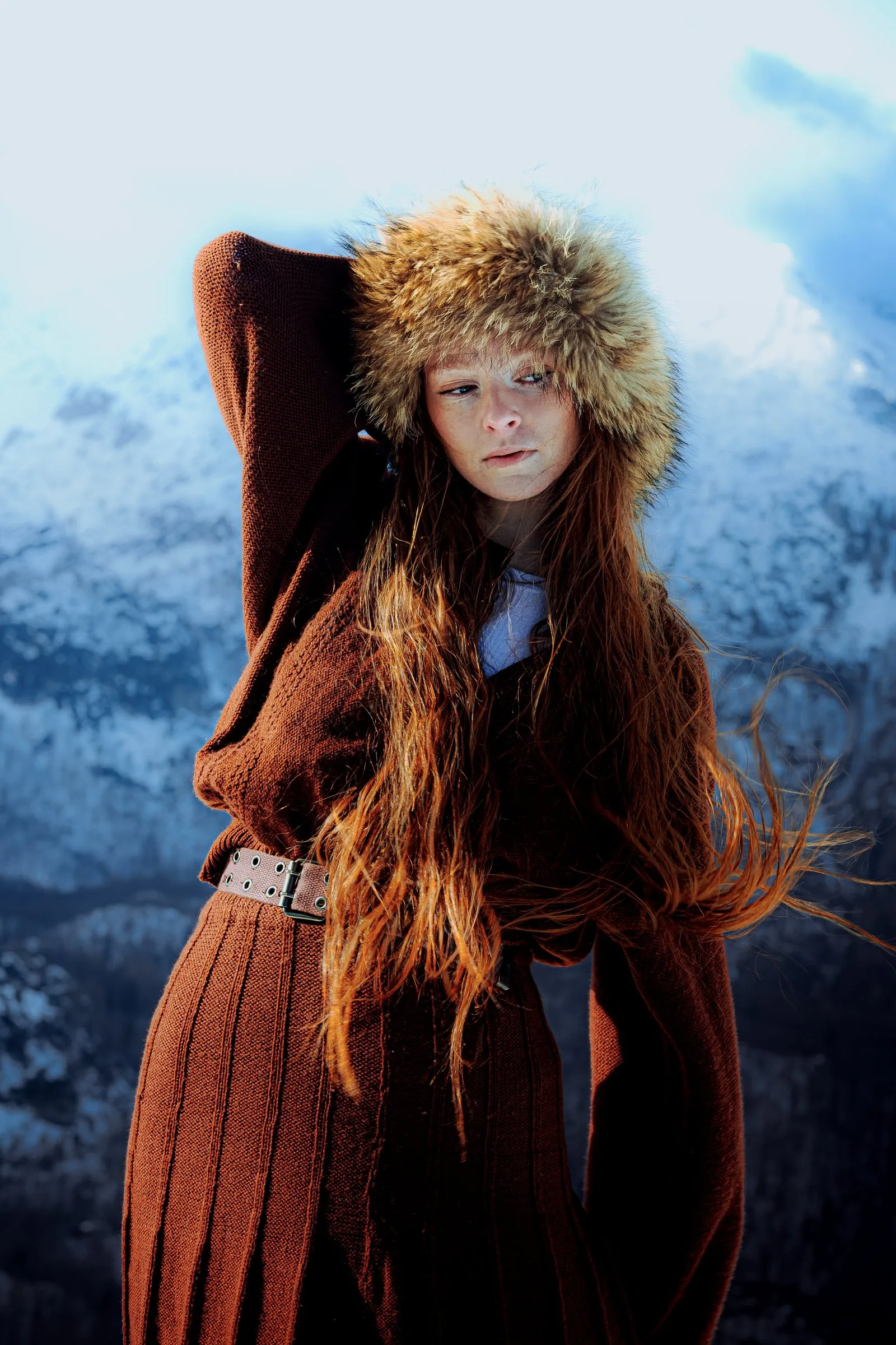 Femme à la chapka de fourrure devant des montagnes enneigées
