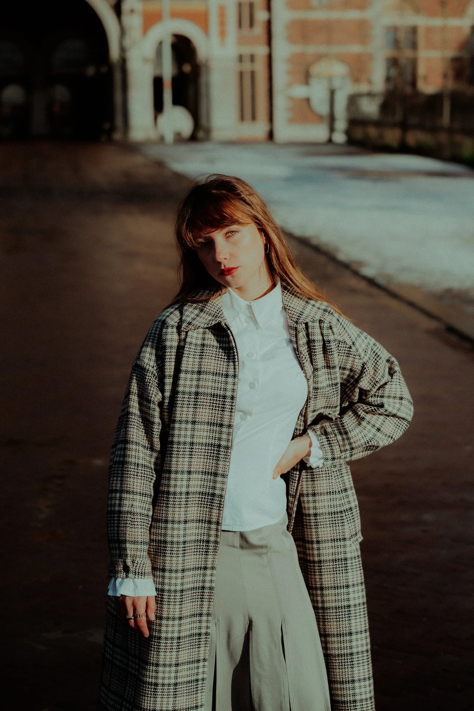 Femme en manteau à carreaux dans une rue de briques