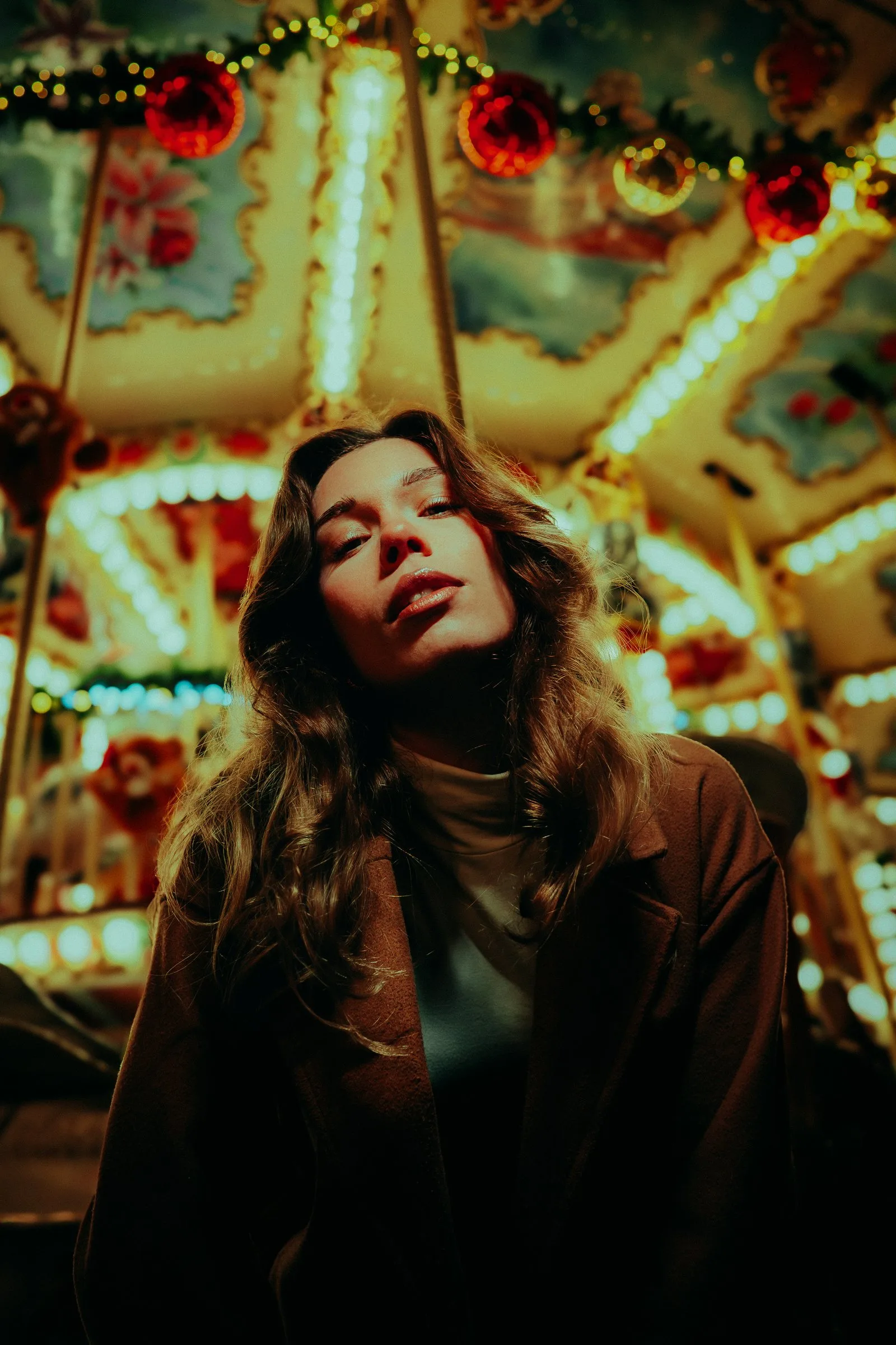 Femme en manteau devant un manège illuminé