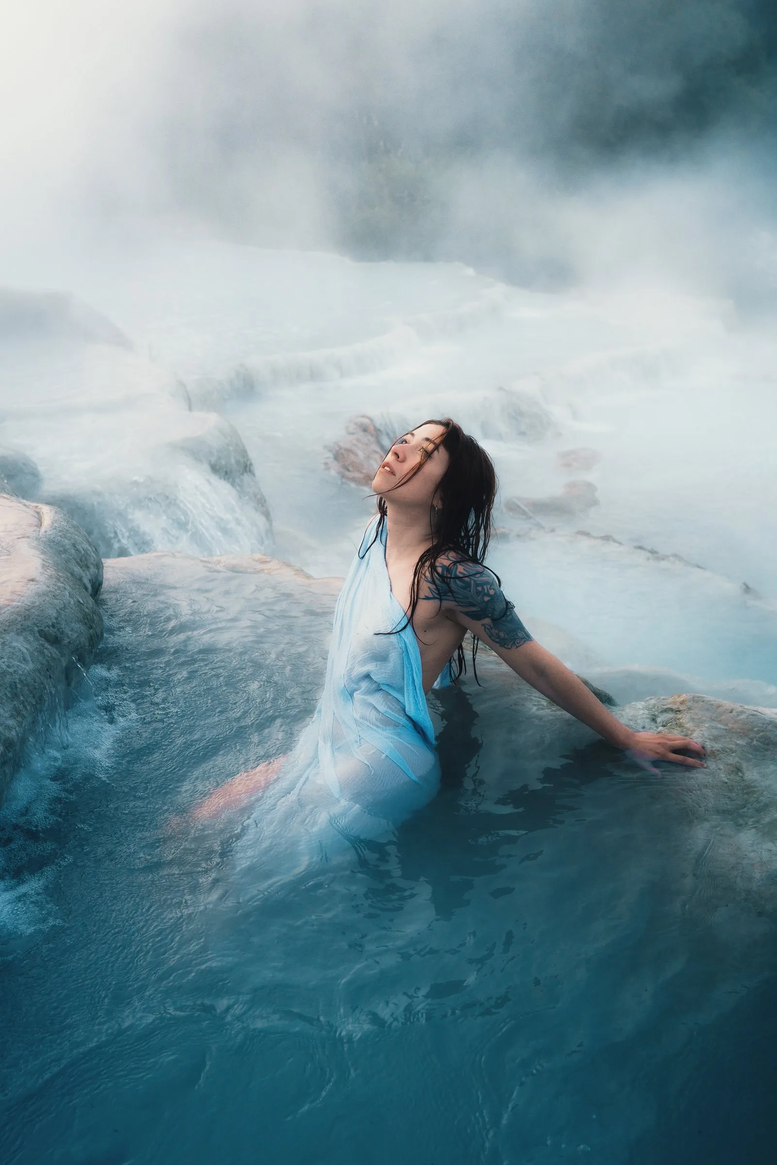 Femme en robe bleue allongée dans l’eau d’une cascade