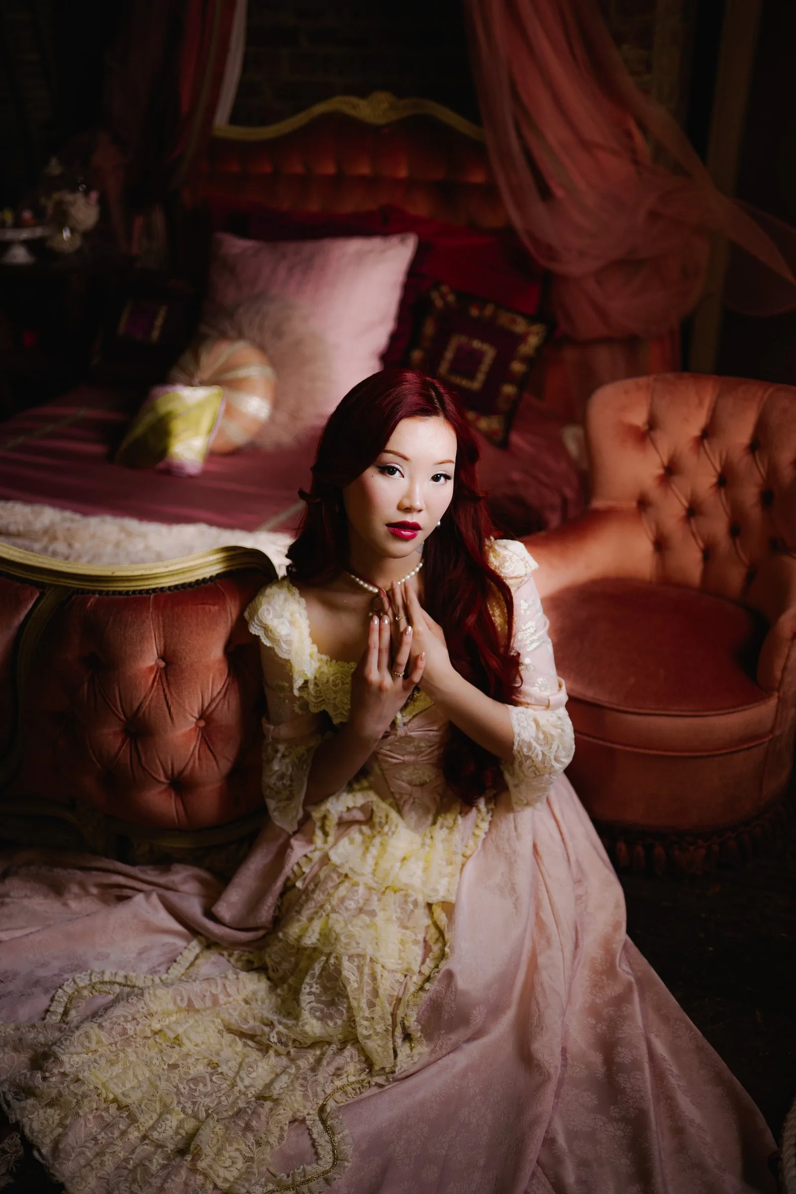 Femme en robe d’époque dans un fauteuil de velours rouge