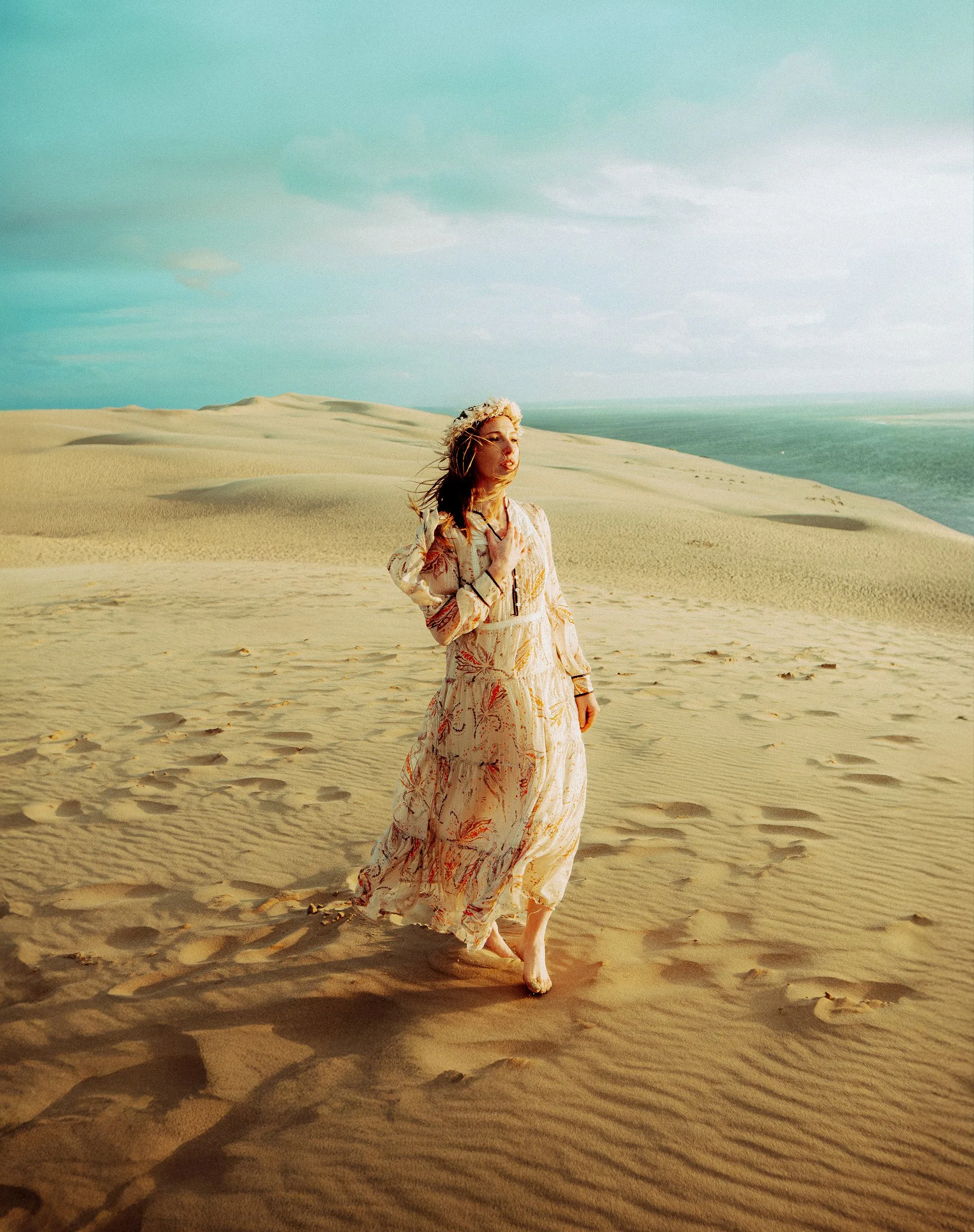 Femme en robe fleurie qui marche dans les dunes de sable