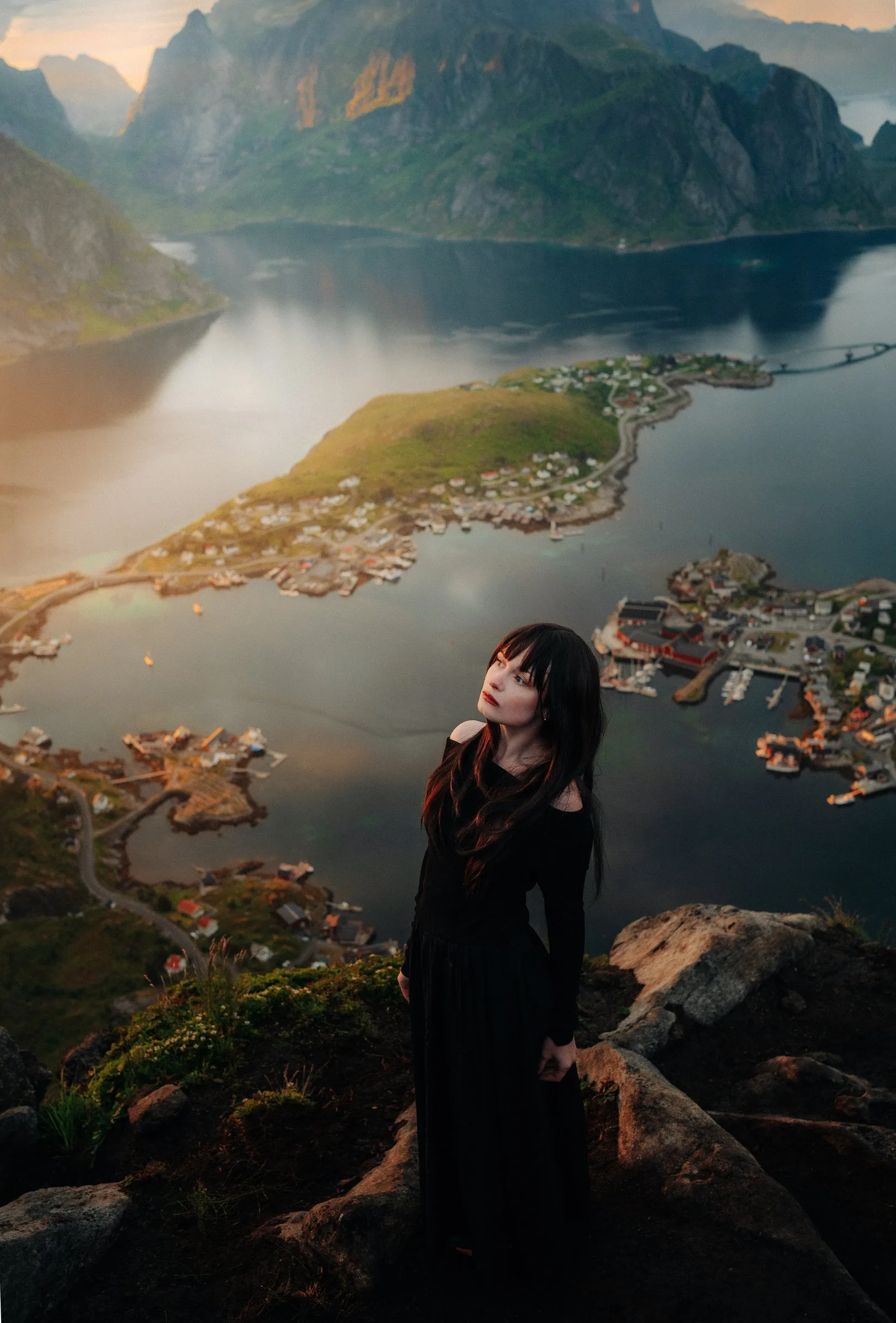 Femme vêtue de noir face à un fjord et un village