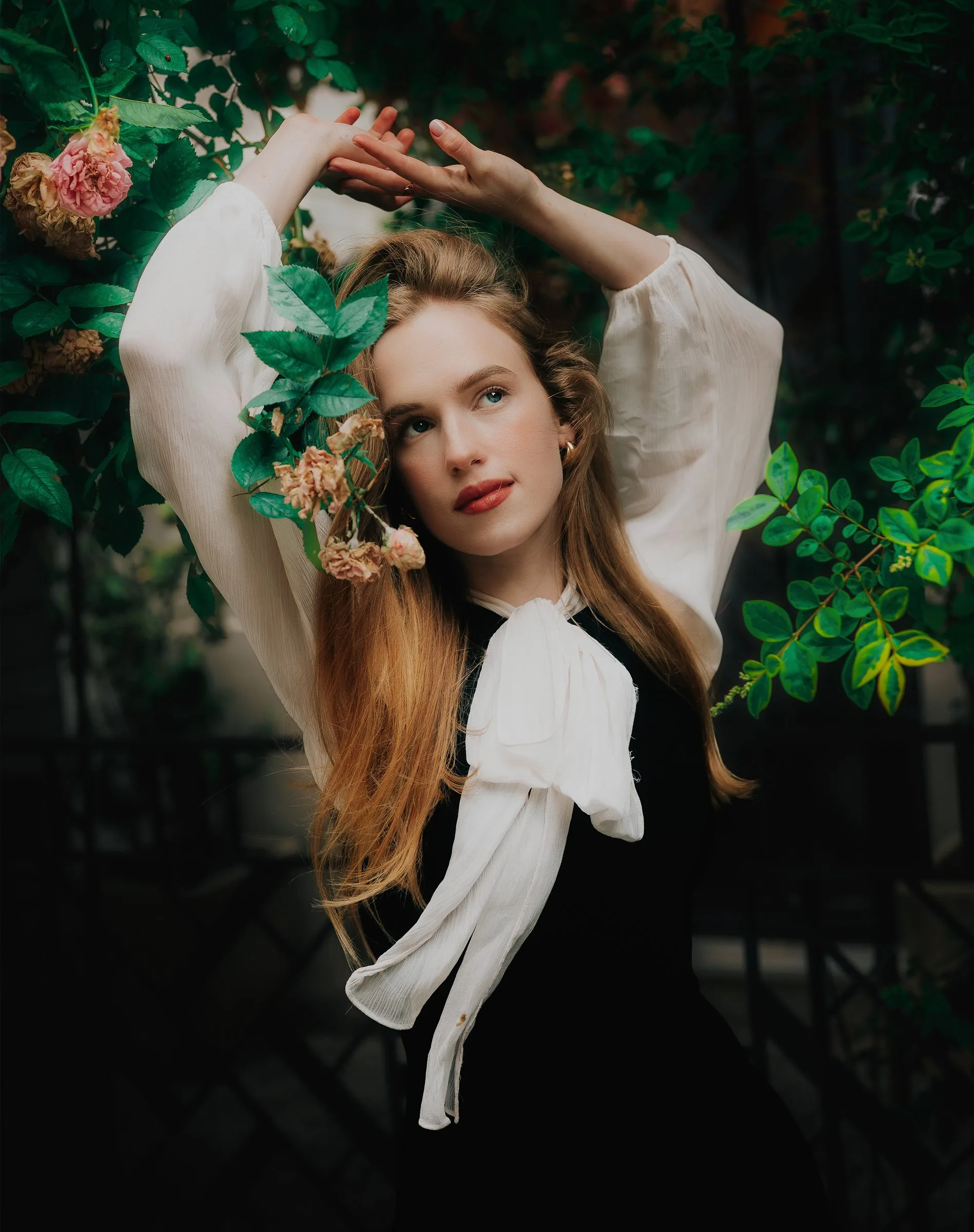 Jeune femme rousse, bras levés parmi les feuillages