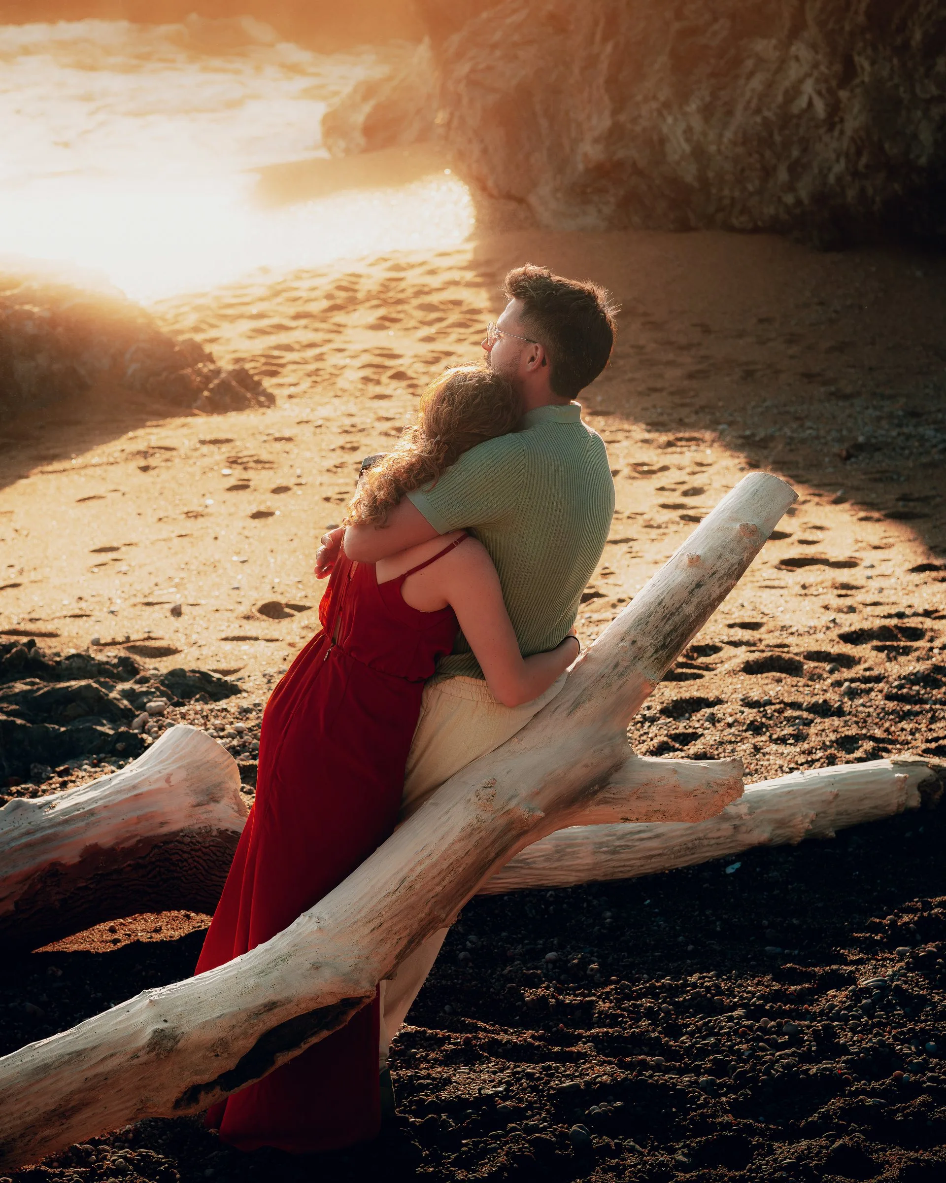 Le couple assis sur un tronc flotté sur la plage