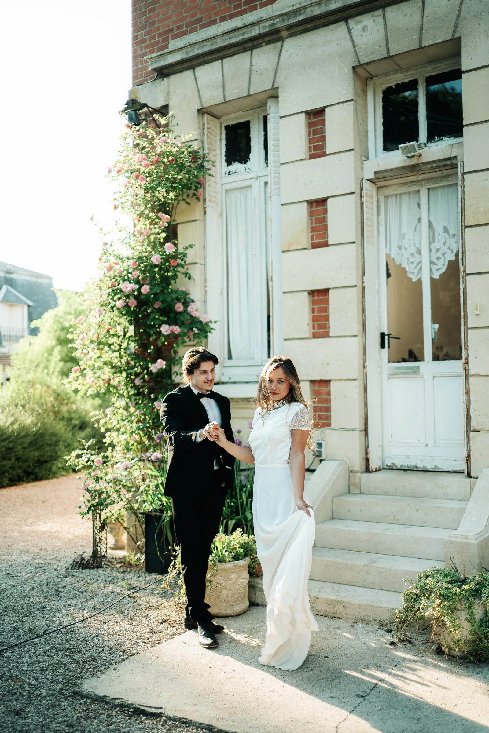 Les fiancés marchent devant une maison fleurie
