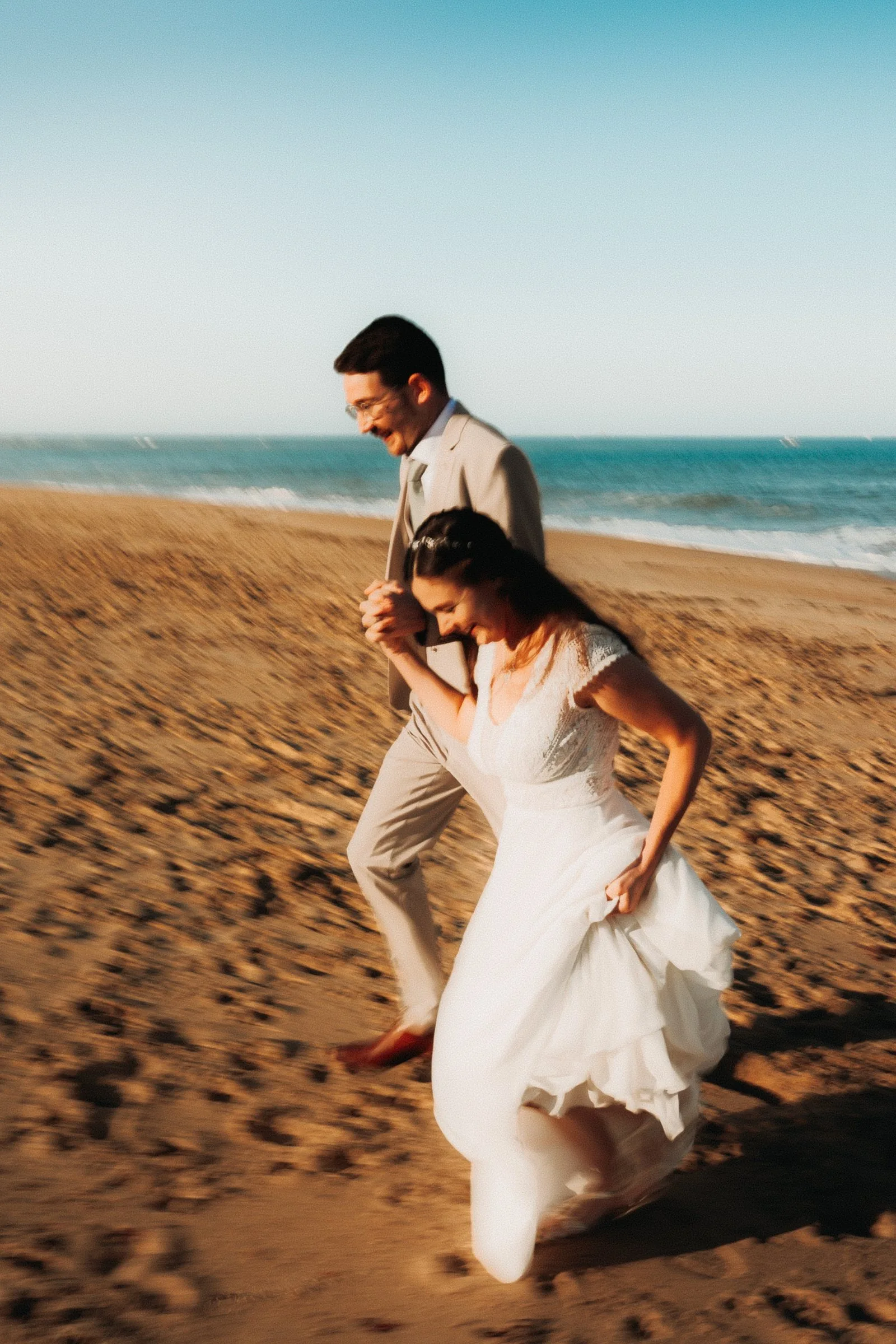 La mariée court sur le sable en riant