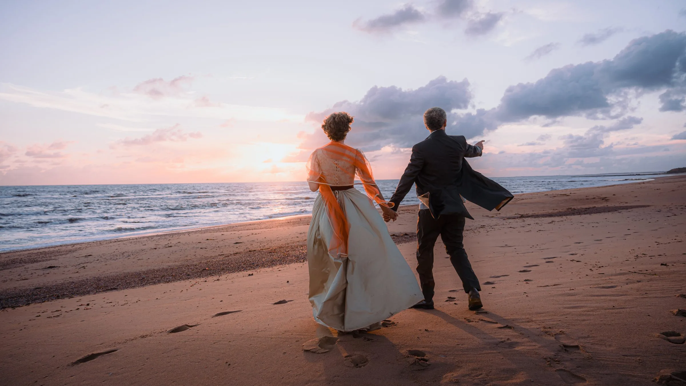 Le couple court sur la plage au coucher du soleil